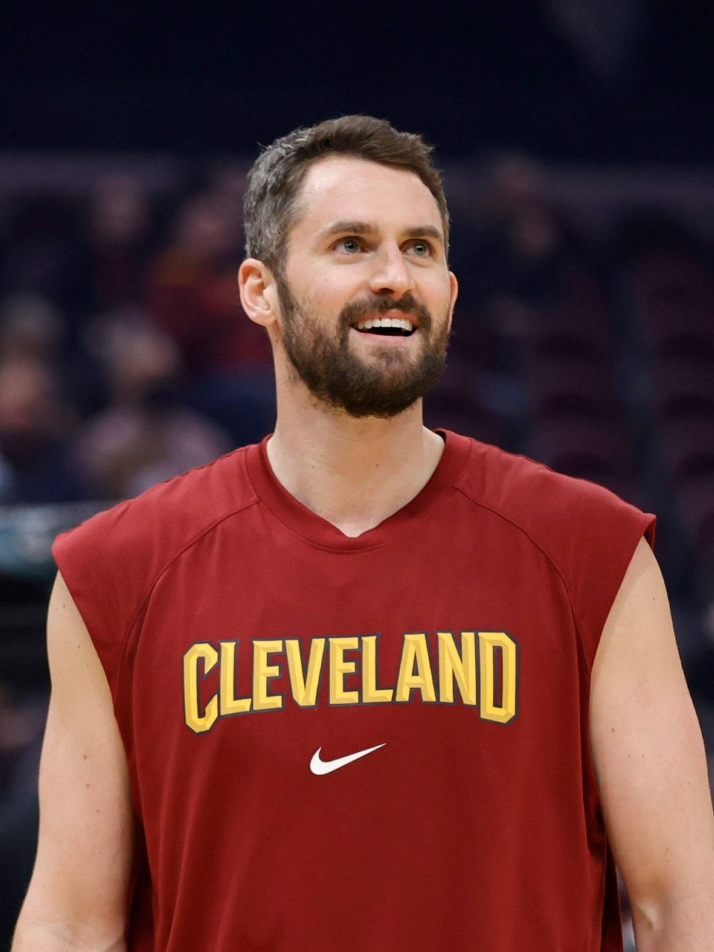 Kevin Love 桌布 壁紙 — 一位微笑的籃球運動員身穿紅色克里夫蘭練習球衣，帶著喜悅的表情向上看。
