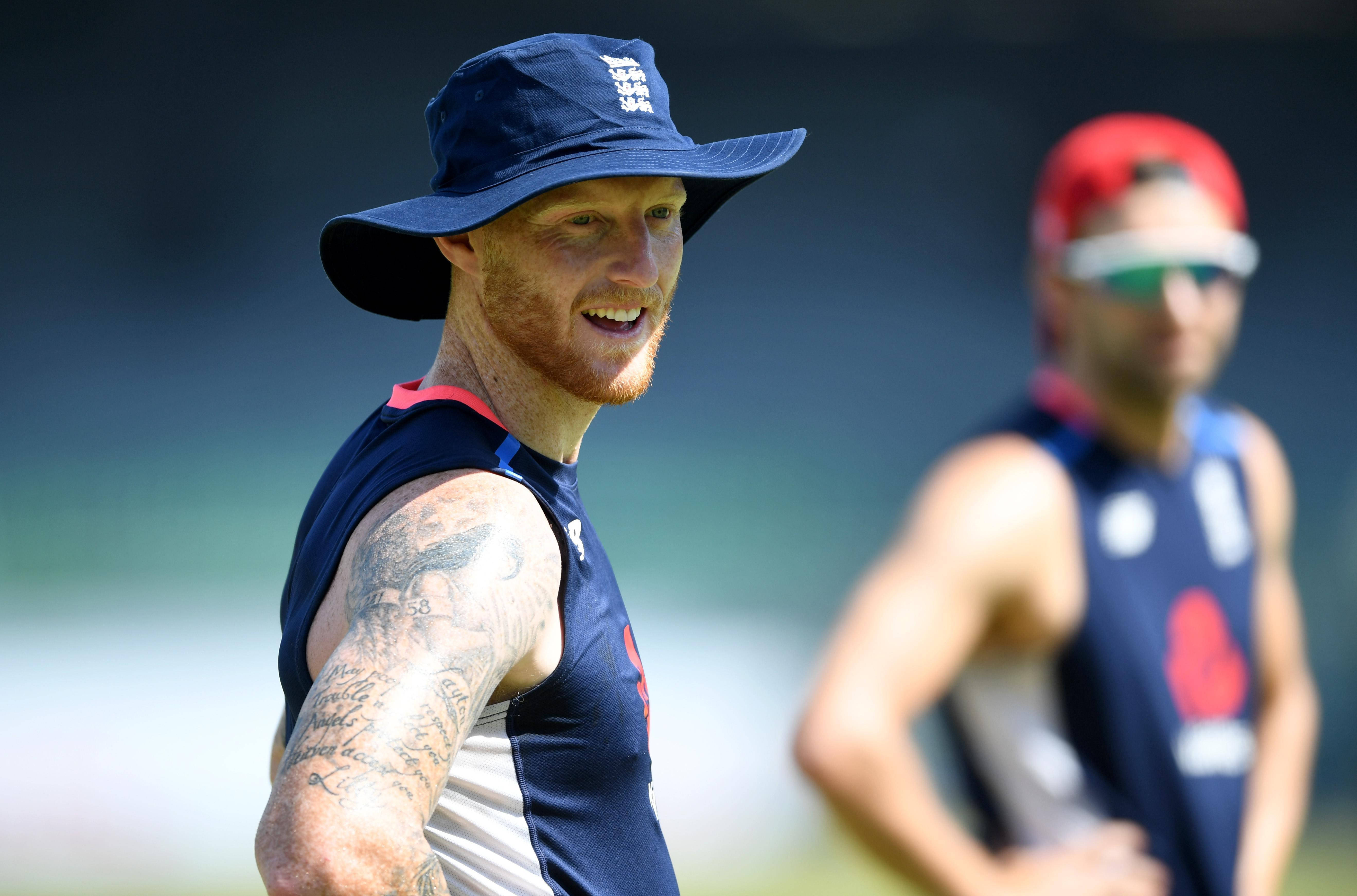 Ben Stokes 桌布 壁紙 — 一位微笑的紅髮板球手，戴著藍色英格蘭帽和無袖球衣，在陽光明媚的訓練中展示他帶有刺青的手臂。