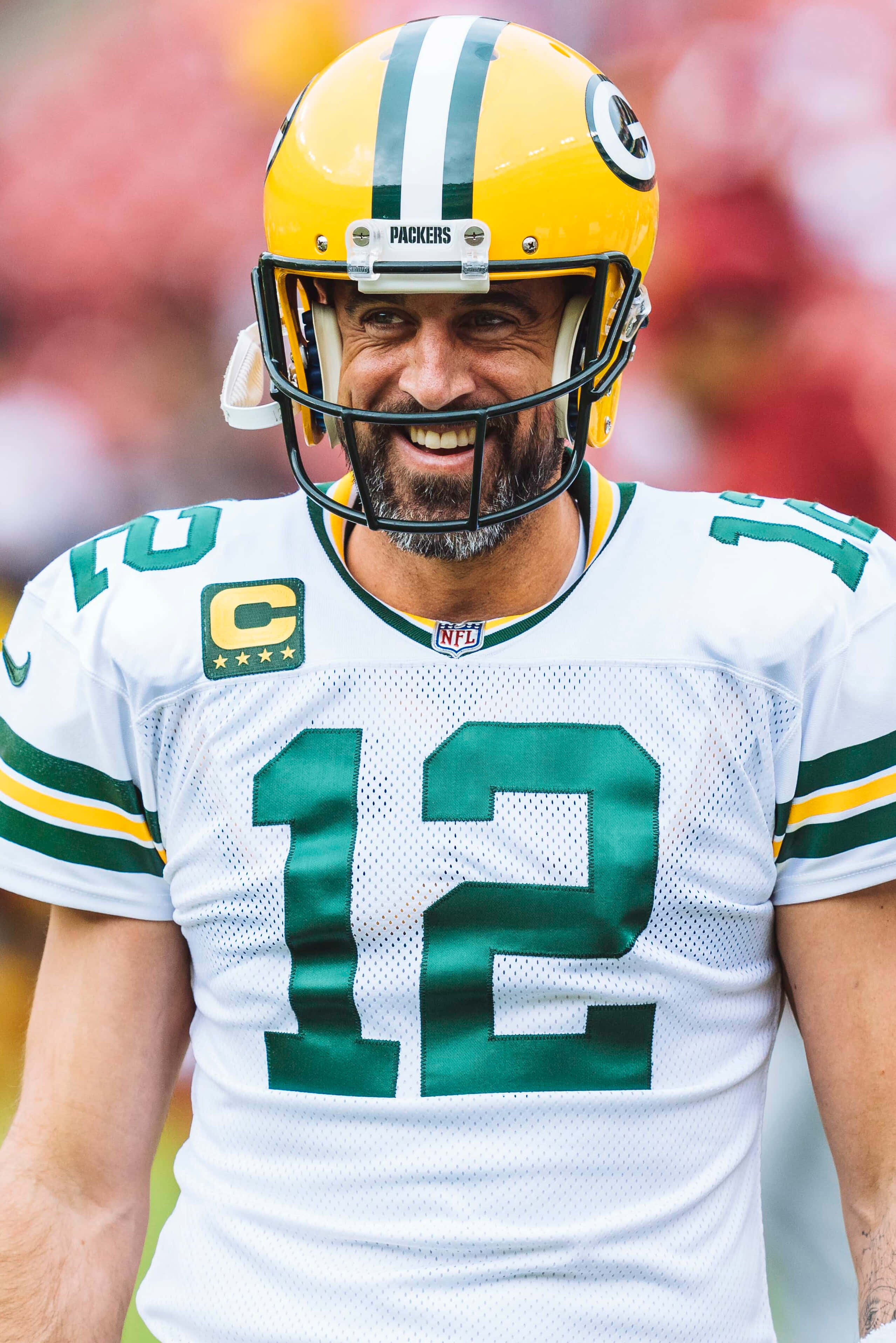 Aaron Rodgers 桌布 壁紙 — 一位微笑的綠灣包裝工四分衛，身穿白色和綠色球衣，號碼12，並帶有隊長 'C' 臂章。