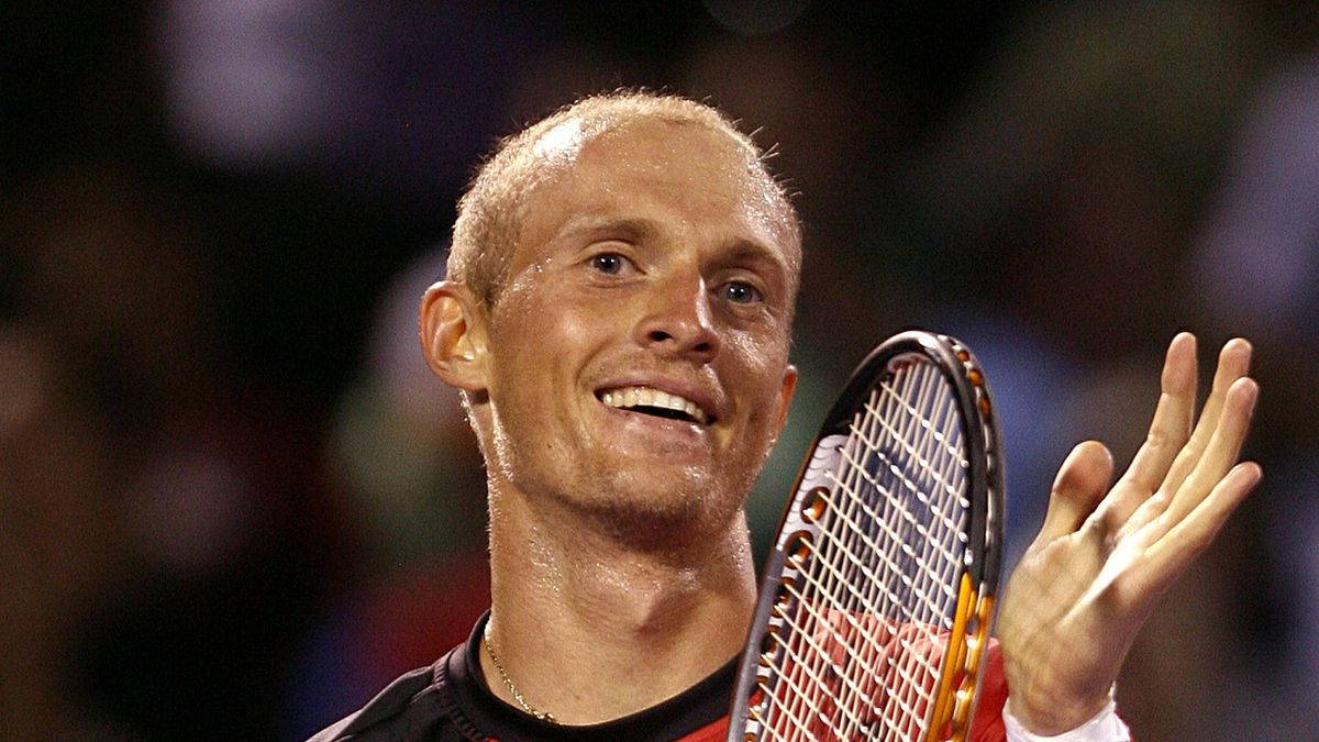 Tennis 桌布 壁紙 — 一位微笑的網球選手在明亮的體育場燈光下，手持球拍向球迷揮手。