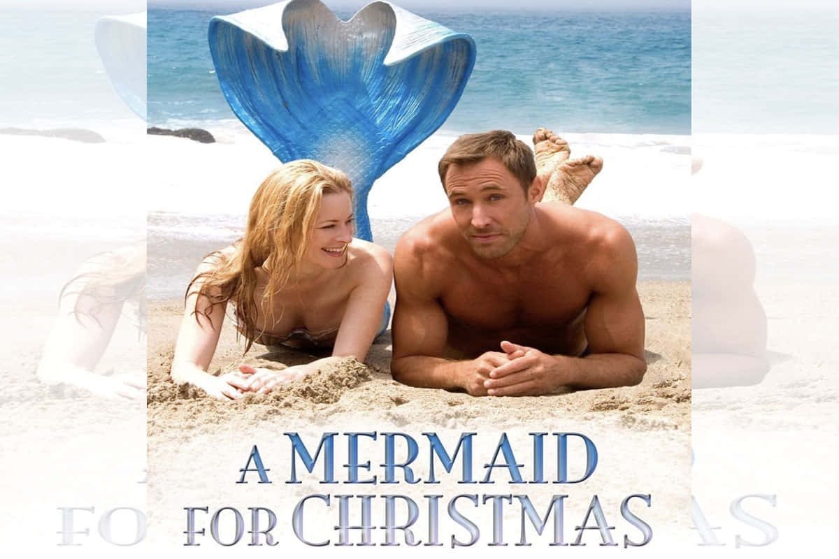 Mermaids 桌布 壁紙 — 一位微笑的美人魚，擁有藍色尾巴，與一名男子在陽光明媚的海灘上休憩，身後是海浪。
