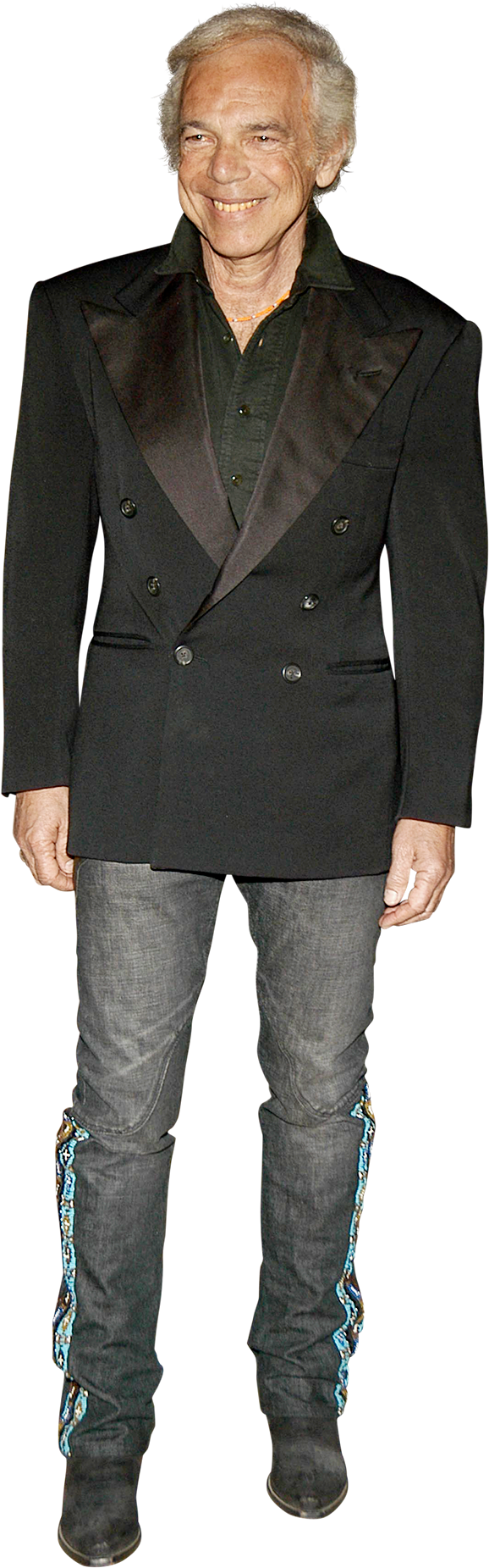 ralph lauren 桌布 壁紙 — 一位微笑的老年男士穿著黑色雙排扣西裝外套和帶有彩色刺繡袖口的牛仔褲，站在黑色背景前。
