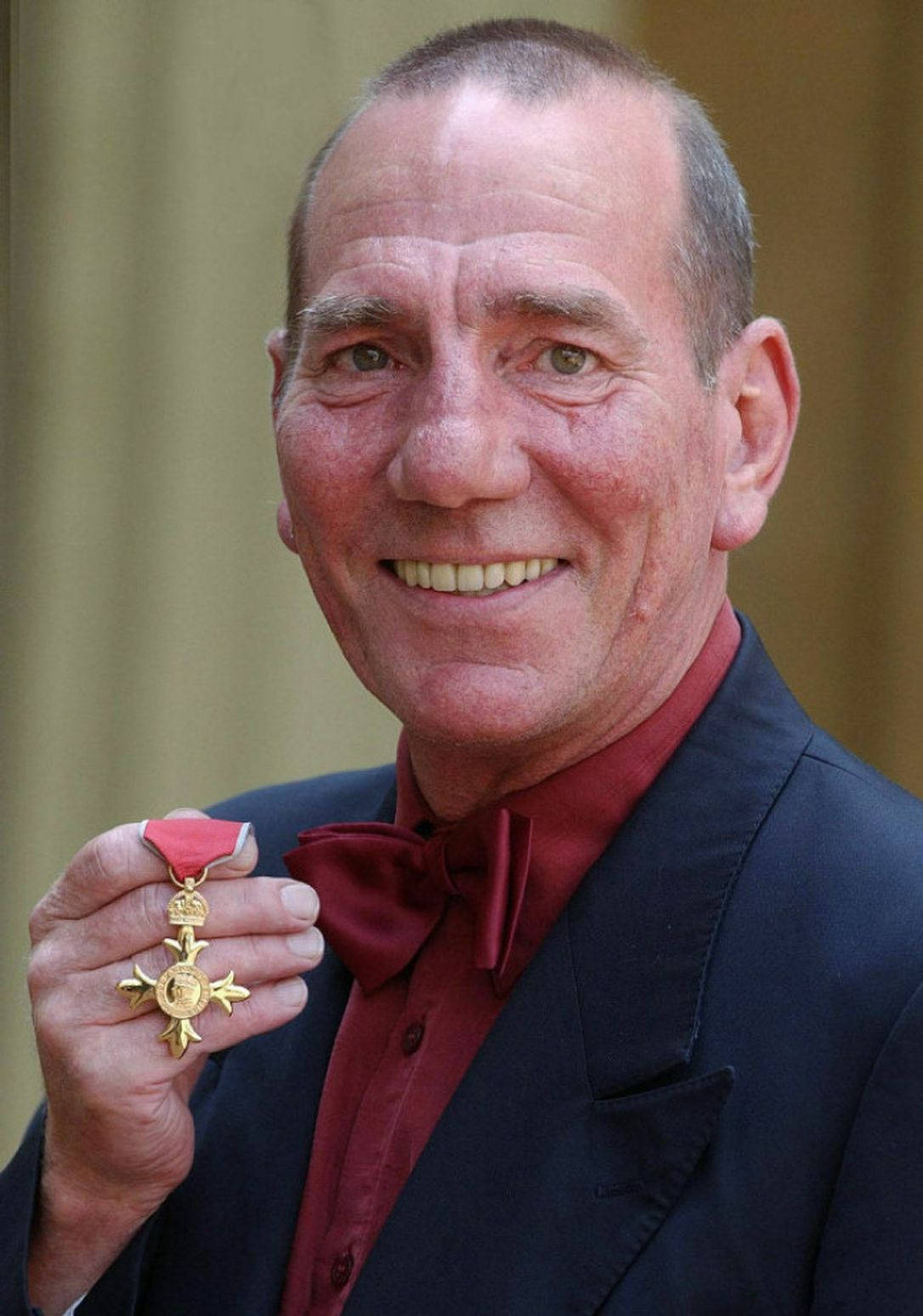 smiling 桌布 壁紙 — 一位微笑的老年男士身穿深色西裝和紅色領結，自豪地展示一條帶有紅色絲帶的金牌。
