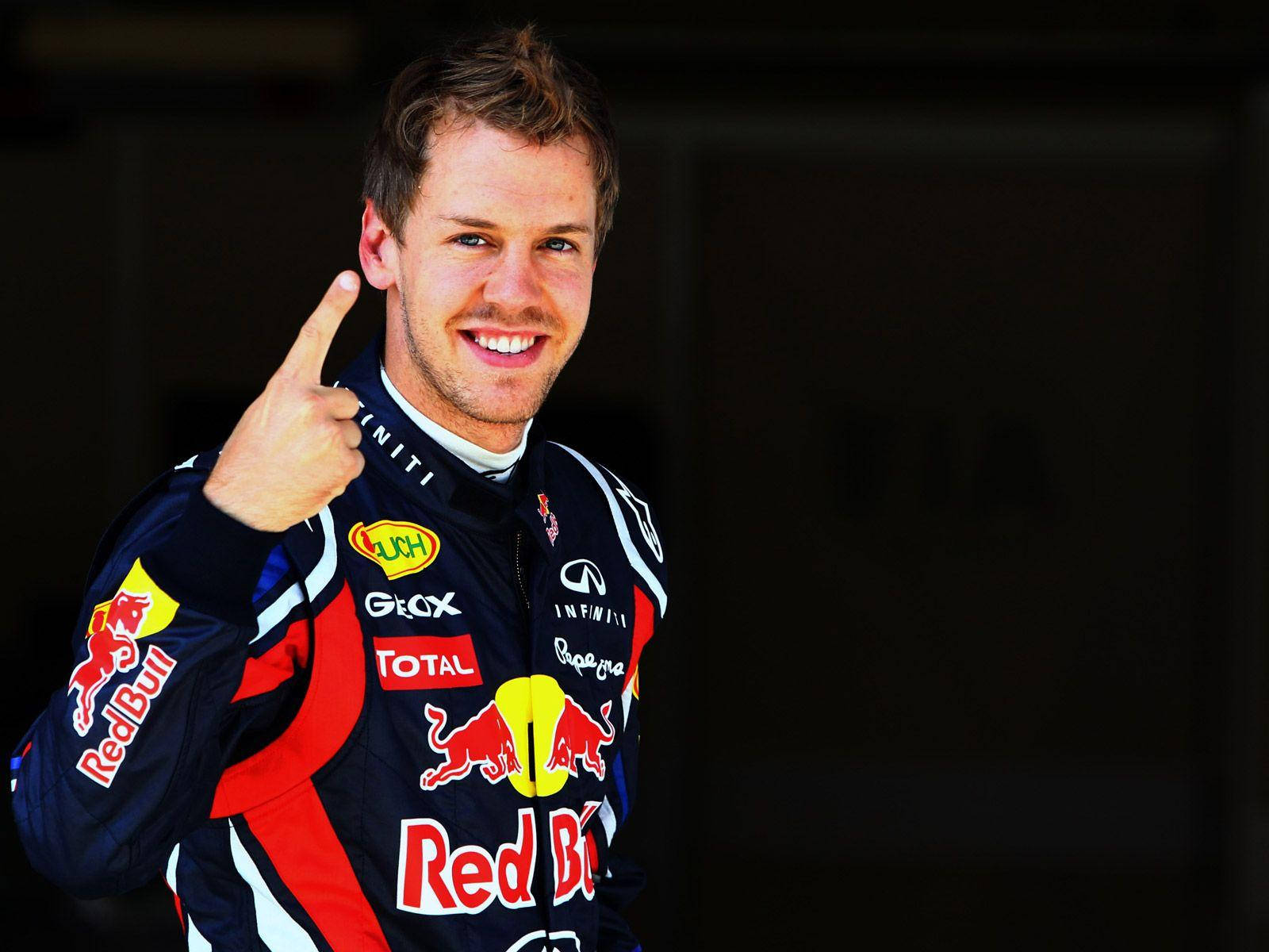 sebastian vettel 桌布 壁紙 — 一位微笑的賽車手身穿Red Bull賽車服，在深色背景前豎起大拇指。