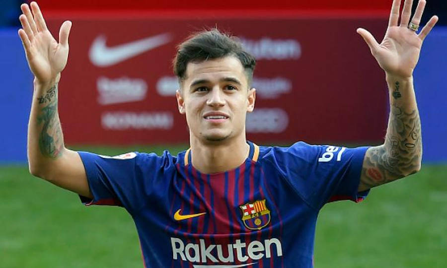 Philippe Coutinho 桌布 壁紙 — 一位微笑的足球運動員身穿藍色條紋球衣，在綠色球場上向球迷揮動雙手，身後有贊助商標誌。