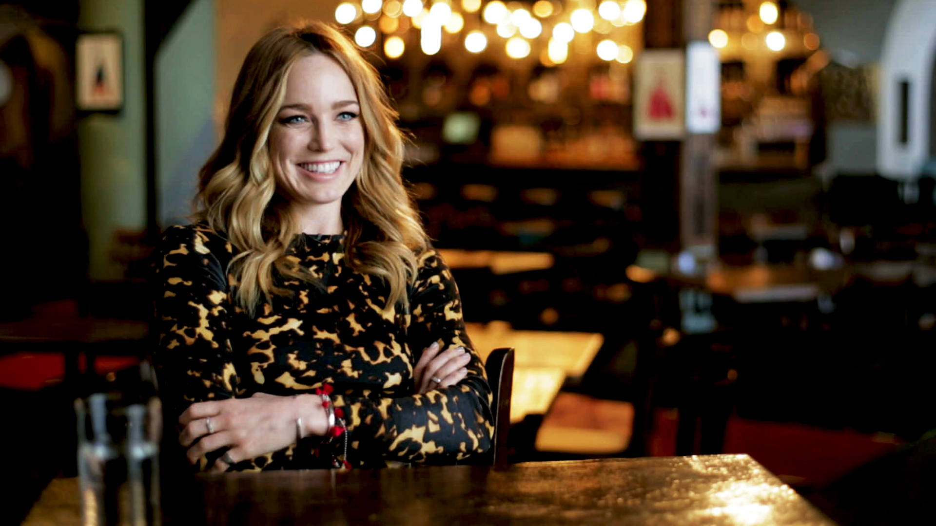 穿著豹紋上衣的女性在舒適的酒吧環境中對著鏡頭微笑。 — Caity Lotz 動圖 壁紙
