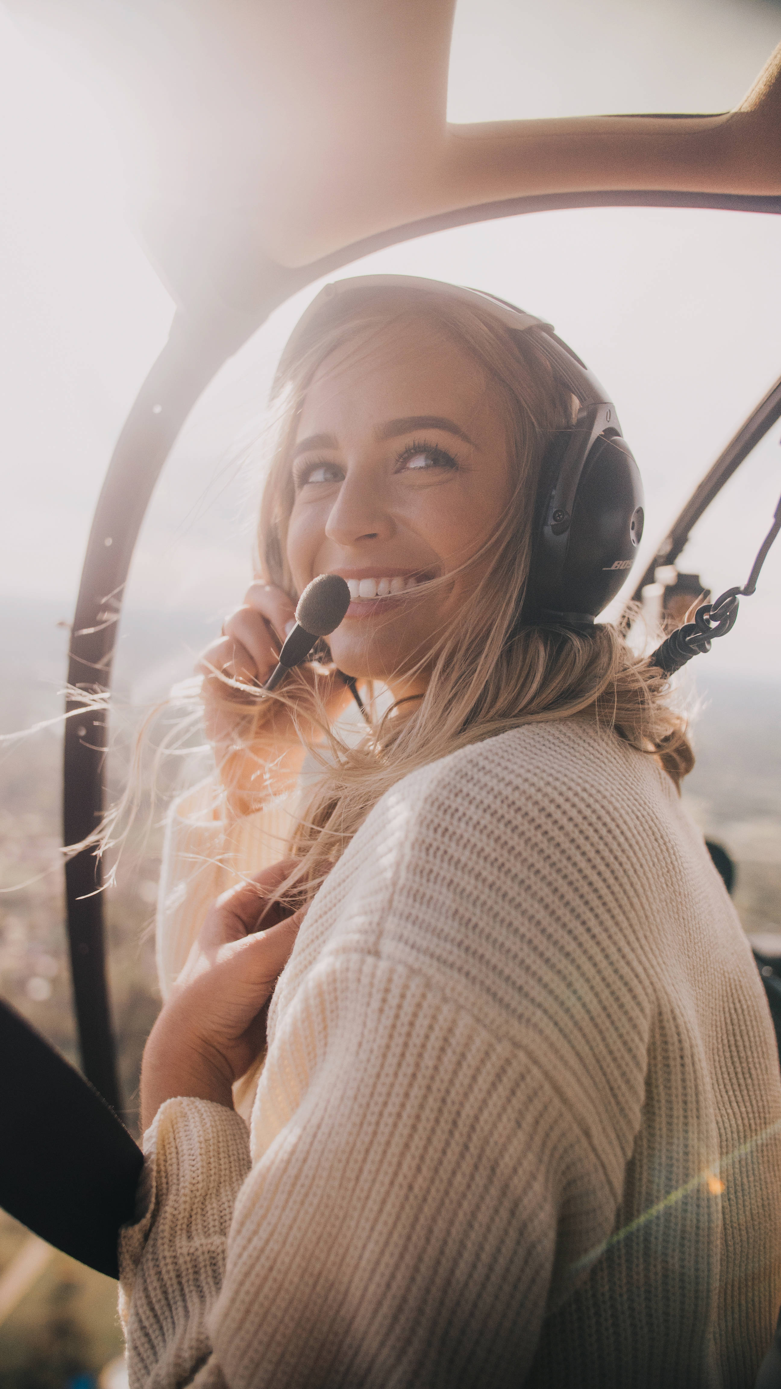 Helicopter 桌布 壁紙 — 一位微笑的金髮女子戴著耳機，在溫暖陽光沐浴的直升機駕駛艙內拿著麥克風。