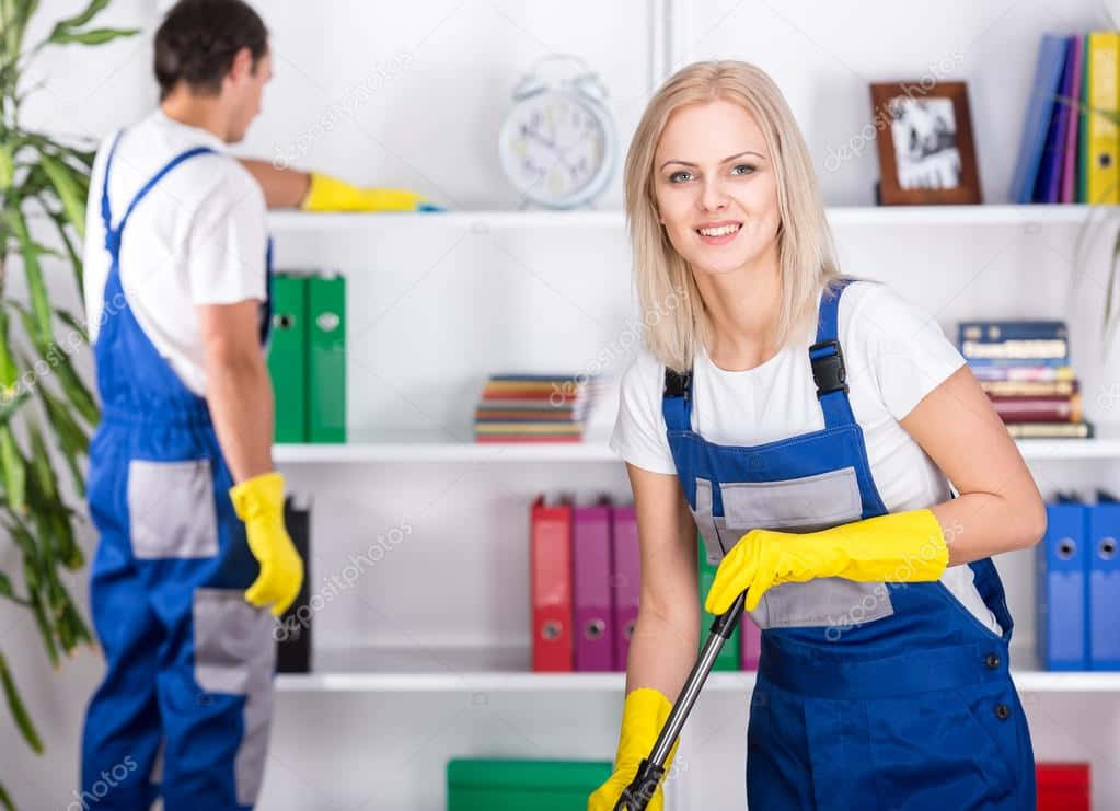 Cleaning 桌布 壁紙 — 一位微笑的金髮女子穿著藍色工裝褲和黃色手套，拿著拖把，而一名男子正在明亮的辦公室裡清潔架子。