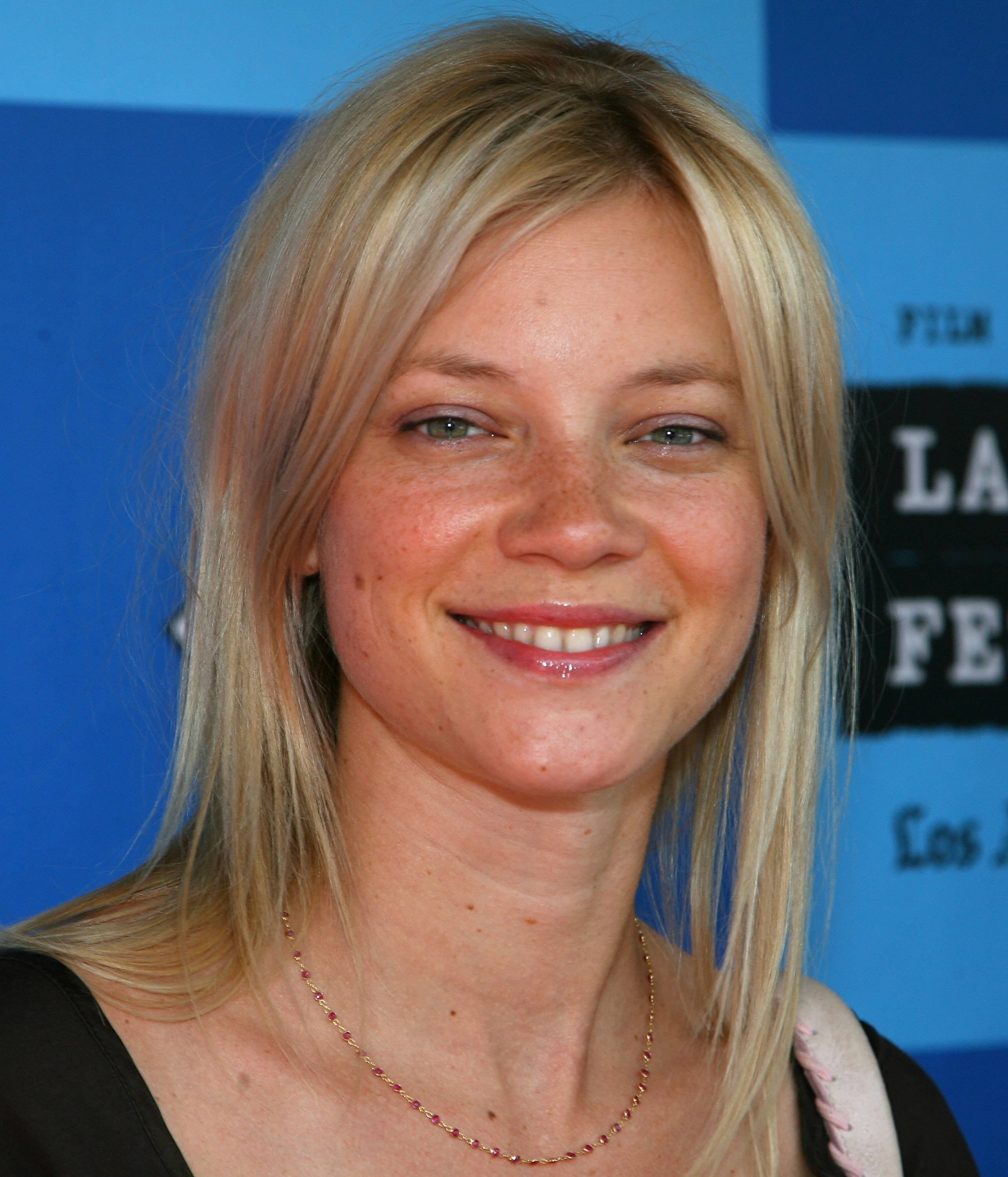 Celebrity 桌布 壁紙 — 一位微笑的金髮女性，臉上有雀斑，戴著精緻的項鍊，站在藍色活動背景前。