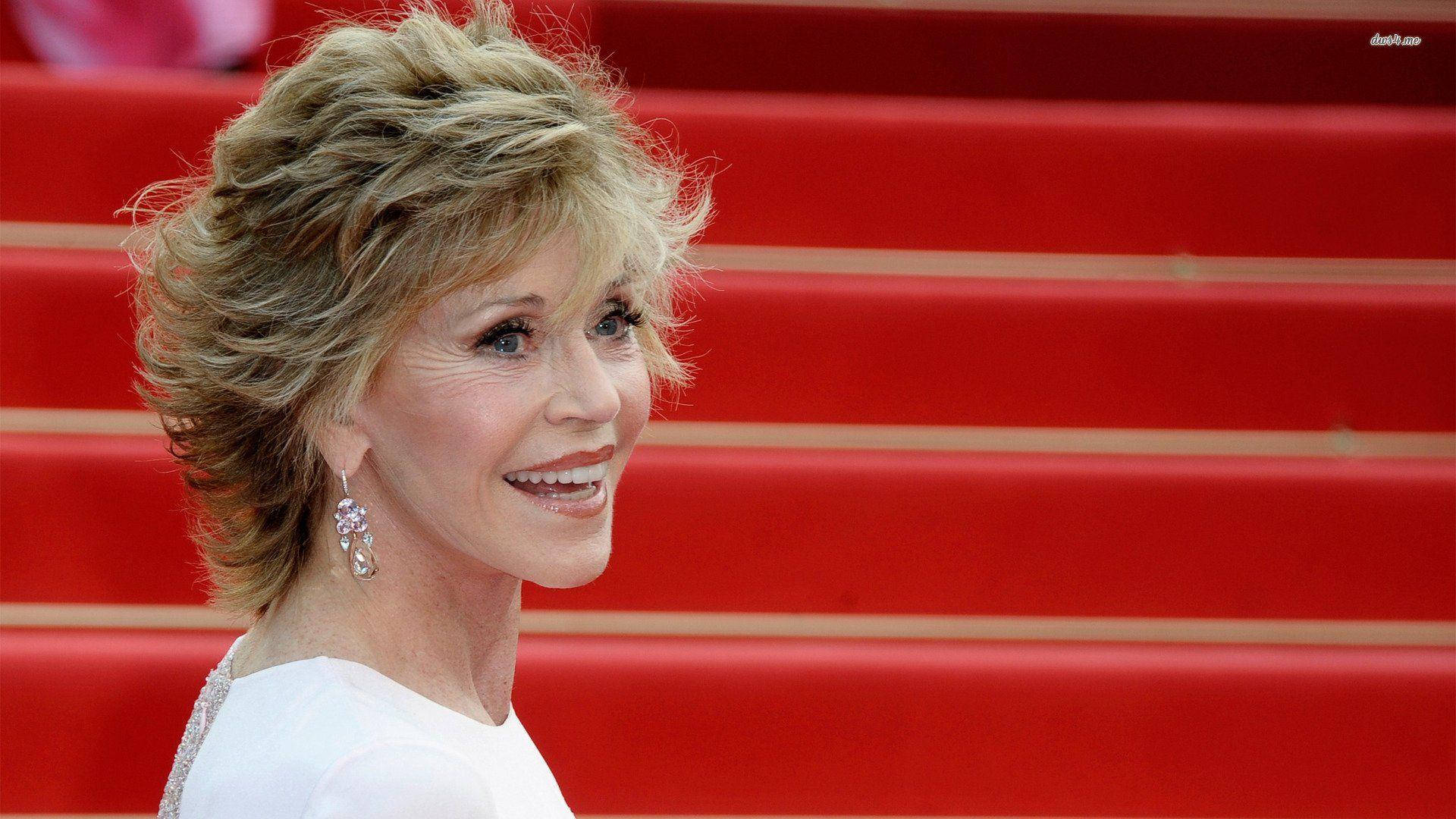 Celebrity 桌布 壁紙 — 一位微笑的金髮女性戴著垂墜耳環，站在充滿活力的紅地毯樓梯上。