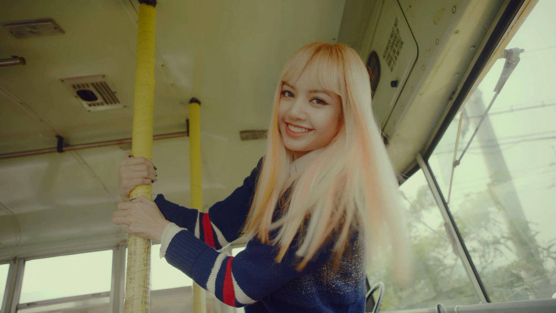 lisa 桌布 壁紙 — 一位微笑的金髮年輕女子在柔和自然光下，於復古電車內握著一根黃色柱子。