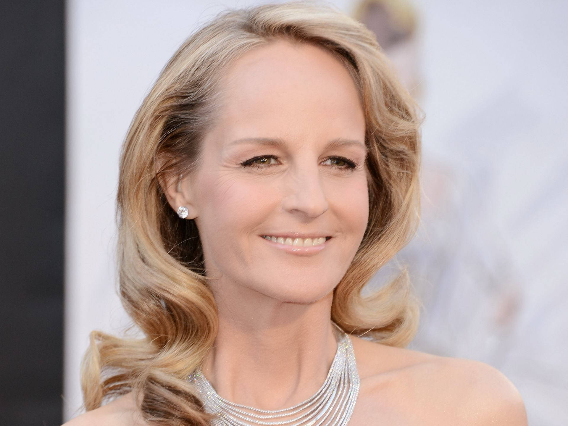 Celebrity 桌布 壁紙 — 一位微笑的金髮波浪髮女性的特寫肖像，戴著閃亮的銀色項鍊和鑽石耳環。