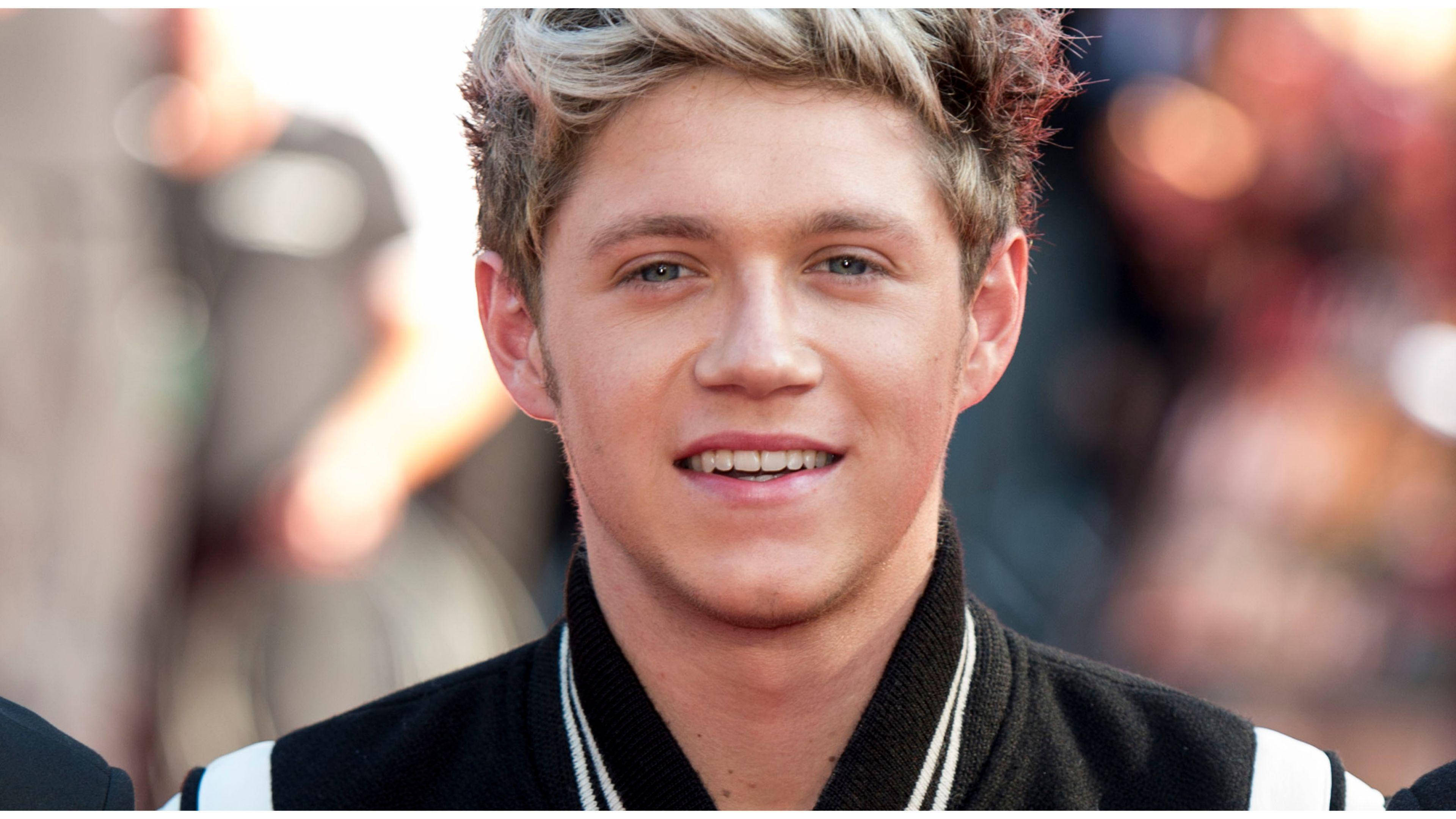 niall horan 桌布 壁紙 — 一位微笑的金髮藍眼年輕男子穿著黑白夾克的近距離肖像。