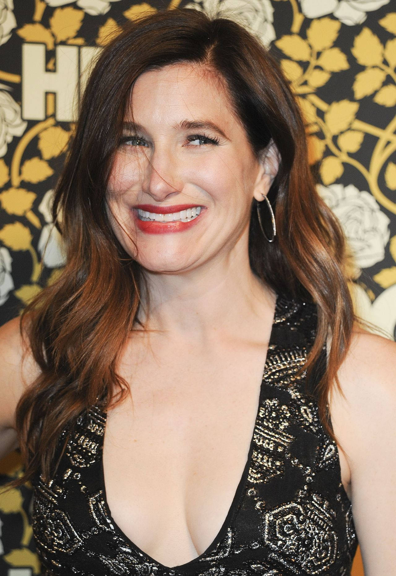Celebrity 桌布 壁紙 — 一位微笑的長棕髮紅唇女性，穿著黑色亮片連衣裙，以花卉壁紙為背景。