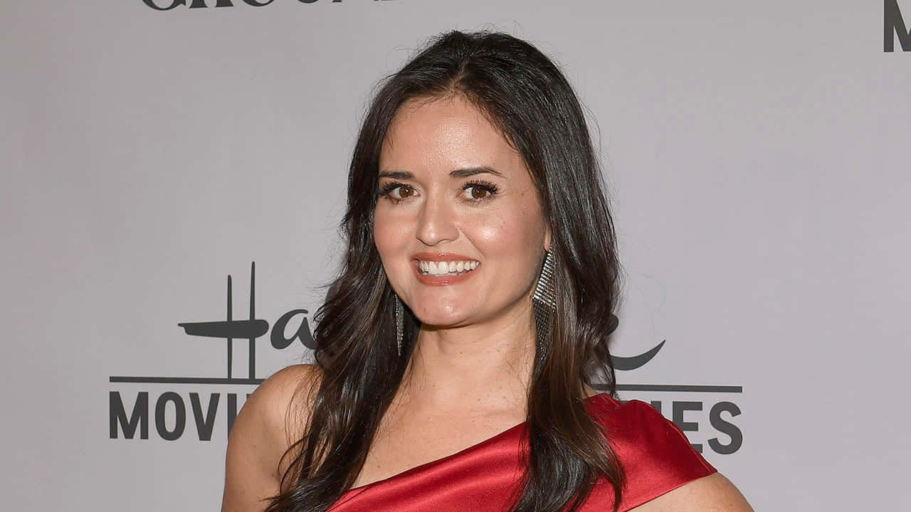 Danica Mckellar 桌布 壁紙 — 一位微笑的長黑髮女性在好萊塢活動中穿著鮮紅色緞面連衣裙。