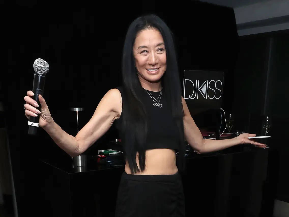 品牌 桌布 壁紙 — 一位微笑的長黑髮女性在帶有'DJ KISS'標誌的DJ台前拿著麥克風和平板電腦。