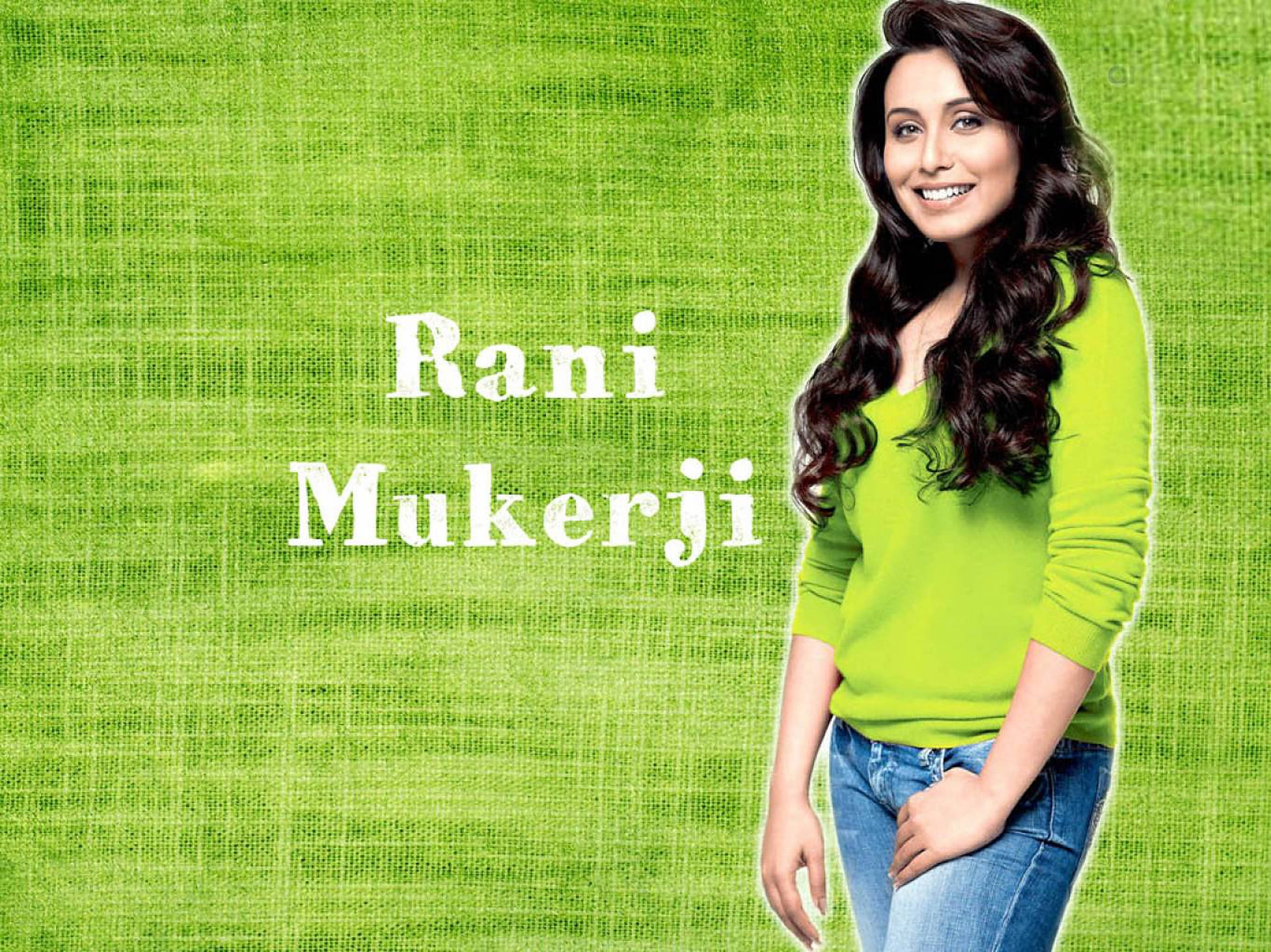 Rani Mukerji 桌布 壁紙 — 一位微笑的長黑髮女性穿著亮綠色毛衣，背景為有紋理的綠色，並以白色文字顯示她的名字。