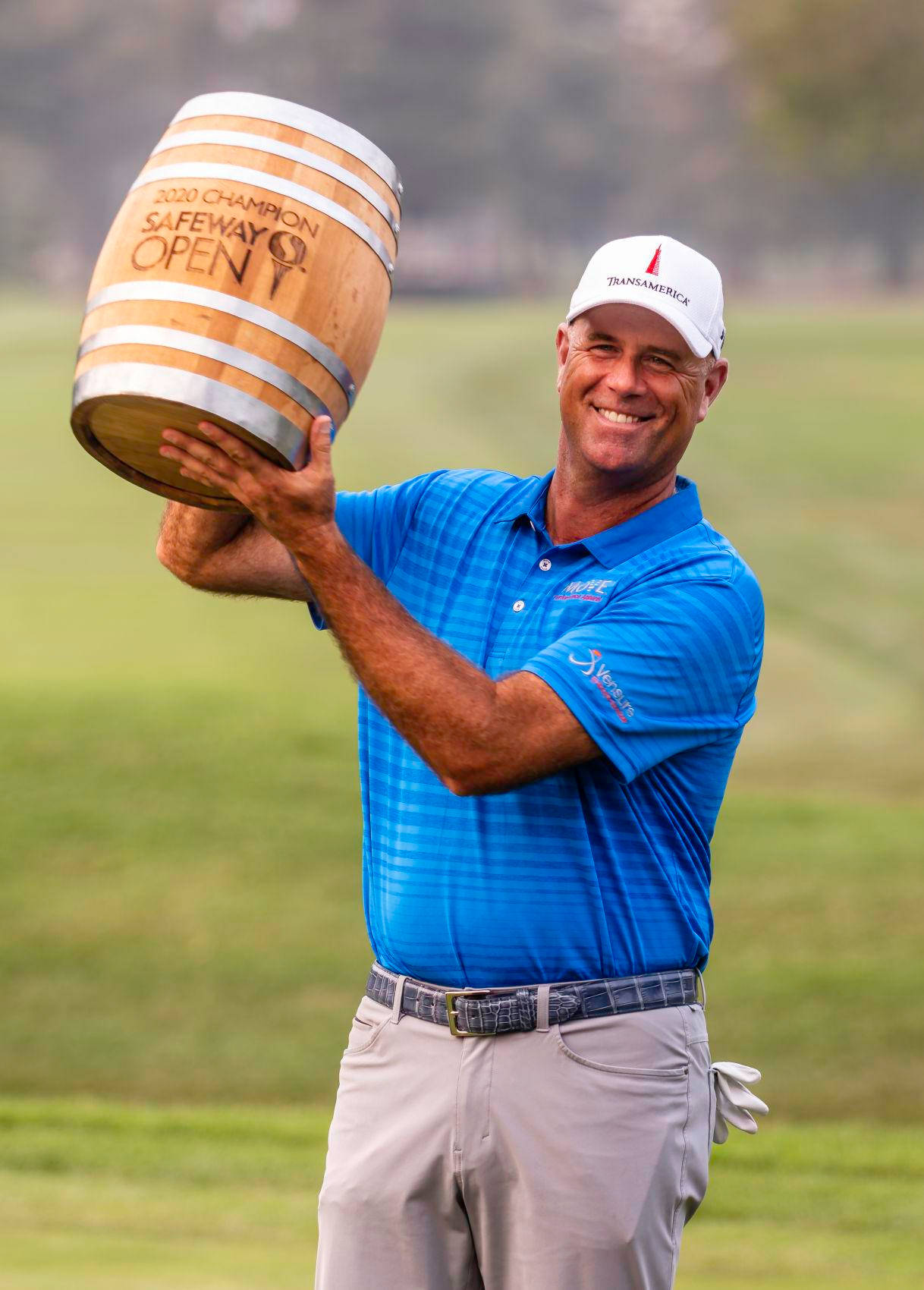 Champion 桌布 壁紙 — 一位微笑的高爾夫球手在翠綠的高爾夫球場上自豪地舉起一個木桶獎盃。