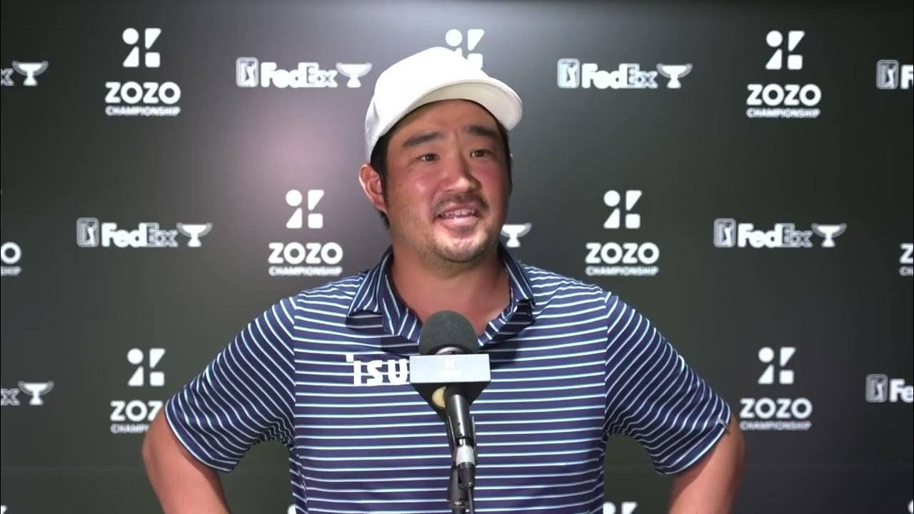 professional 桌布 壁紙 — 一位微笑的高爾夫球手穿著條紋Polo衫和白色帽子，在記者會上對著麥克風講話，身後有ZOZO和FedEx標誌。