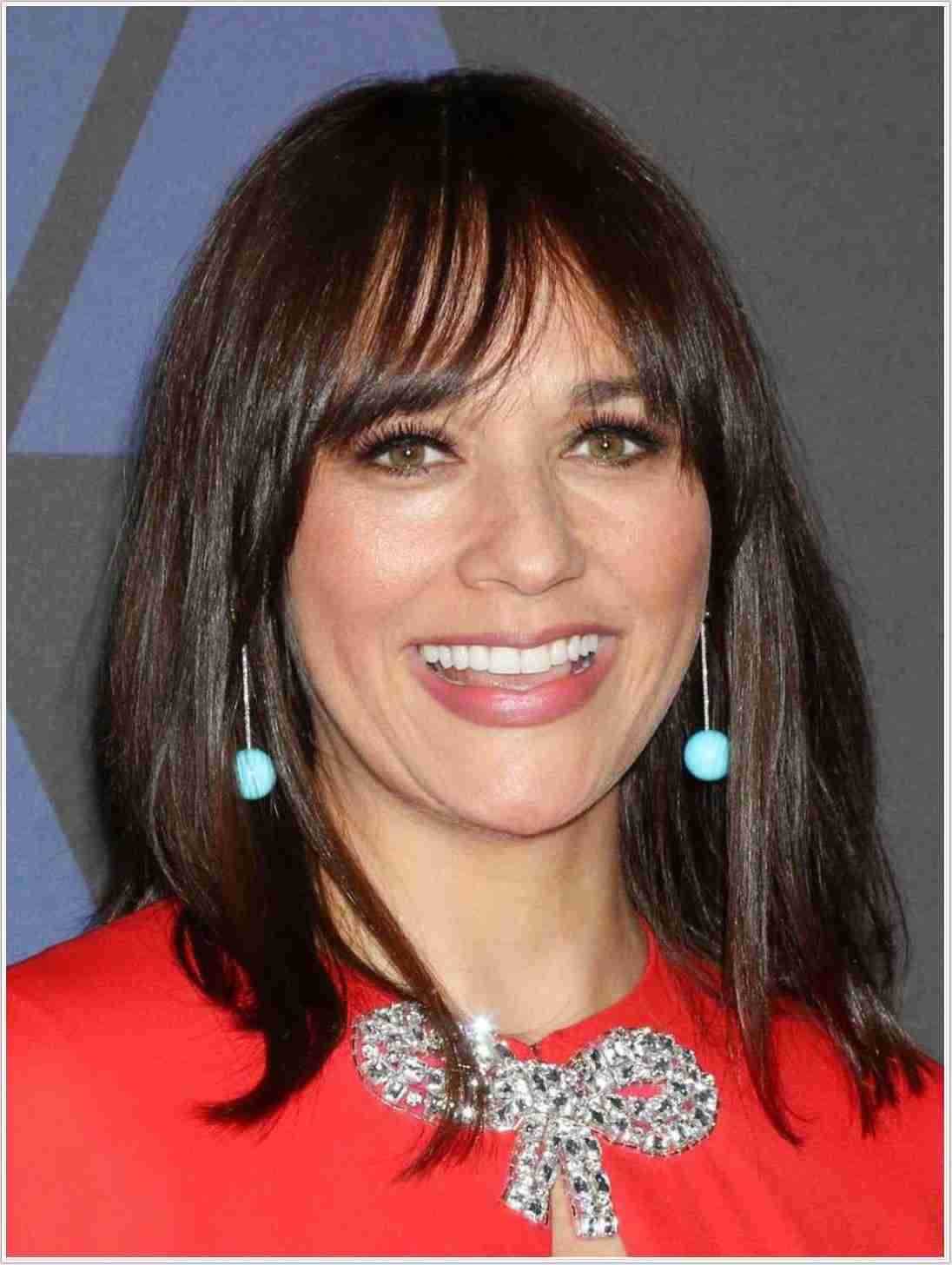 Celebrity 桌布 壁紙 — 一位微笑的黑髮齊瀏海女性，身穿紅色上衣，佩戴閃亮蝴蝶結項鍊和綠松石耳環。