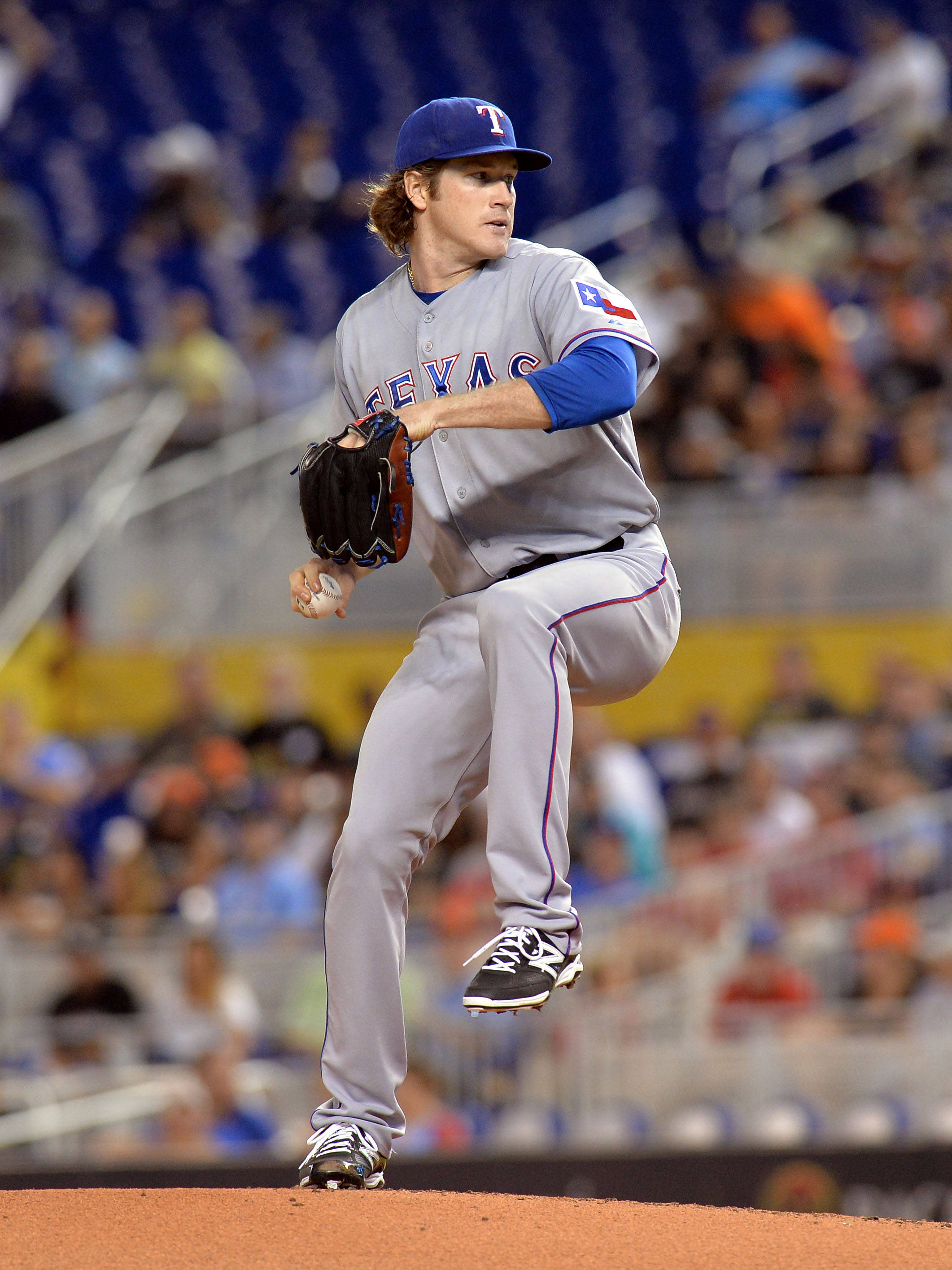 Texas Rangers 桌布 壁紙 — 一位德州遊騎兵投手在棒球投手丘上投球中，背景是模糊的球場觀眾。