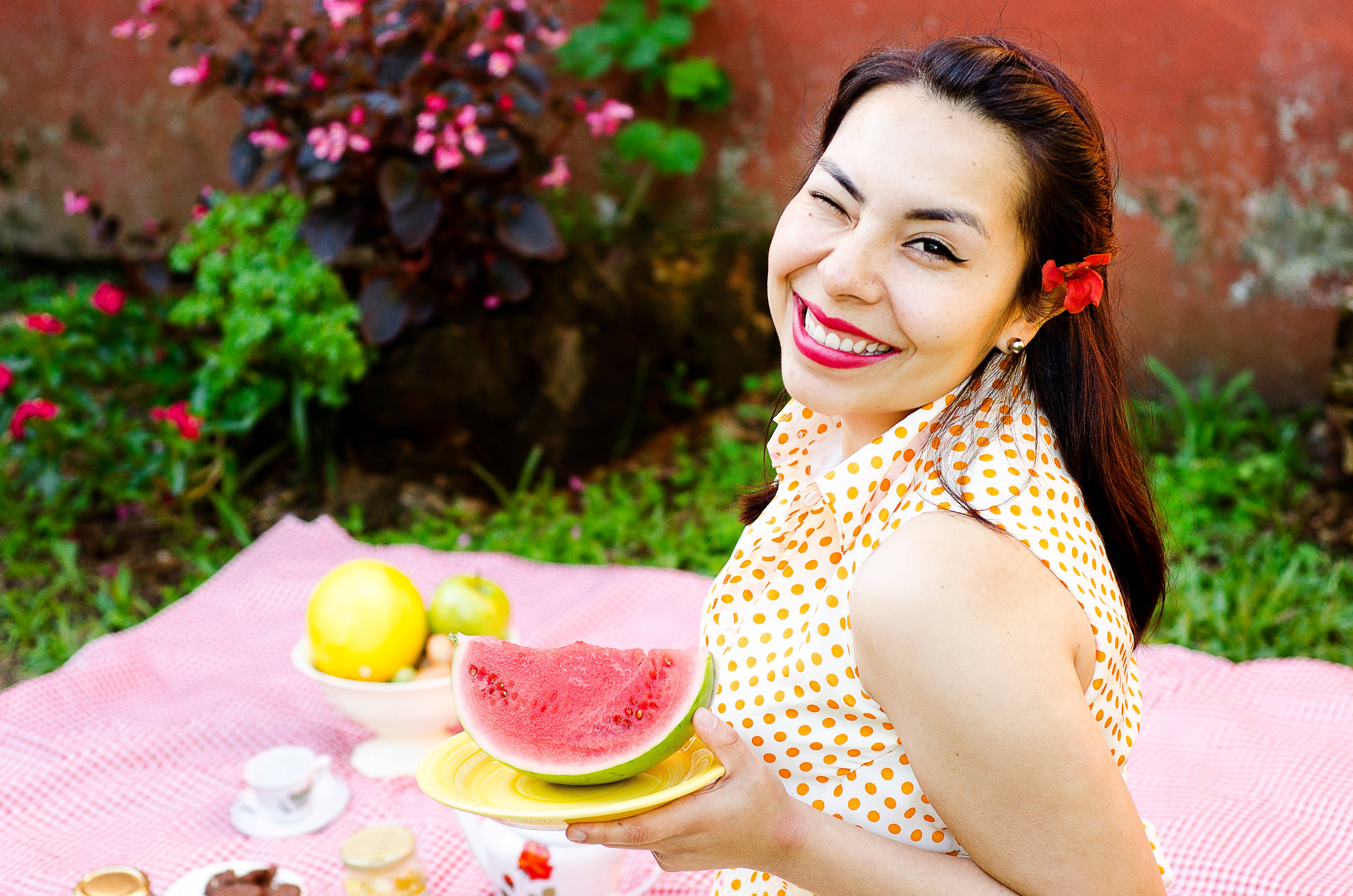 Watermelon 桌布 壁紙 — 一位快樂的女人在陽光明媚的花園野餐中拿著一片西瓜眨眼。