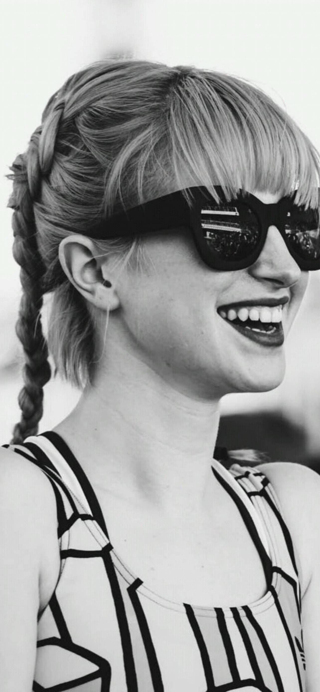Hayley Williams 桌布 壁紙 — 一位快樂的女士，辮子頭髮和太陽眼鏡，在引人注目的黑白肖像中閃耀。