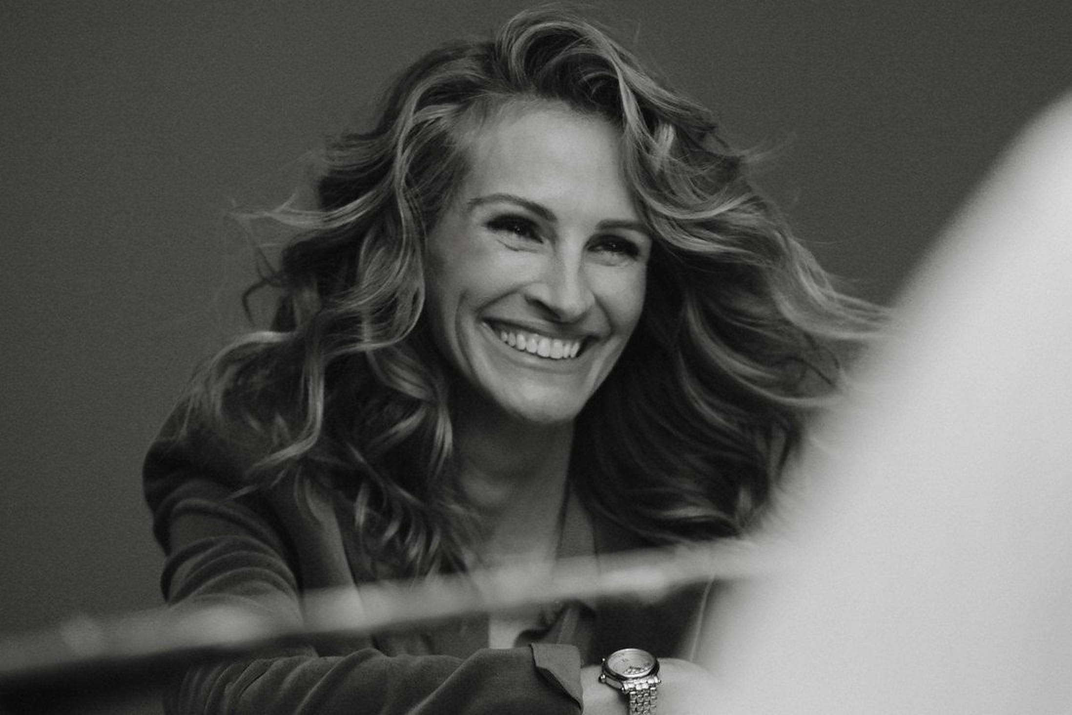 Julia Roberts 桌布 壁紙 — 一位快樂的女性，秀髮飄逸，在柔和光線的黑白肖像中燦爛微笑。