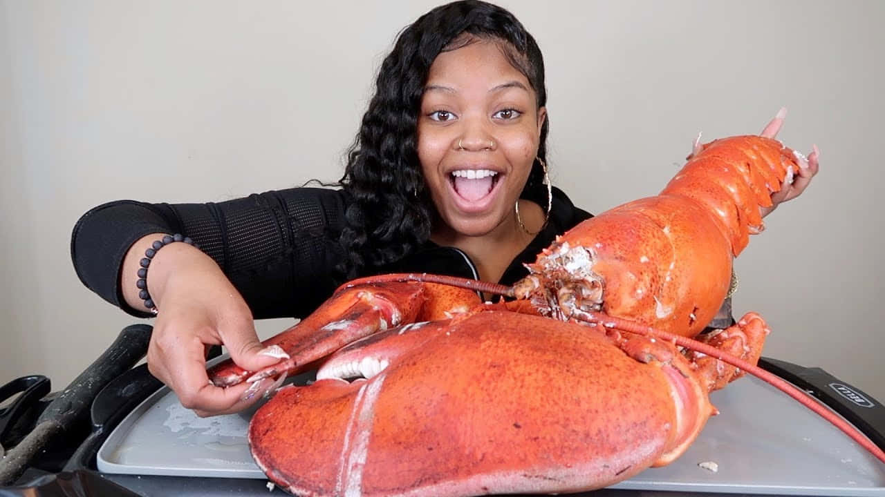 Lobster 桌布 壁紙 — 一位快樂的女性在室內熱情地拿著托盤上的一隻巨大的熟龍蝦。