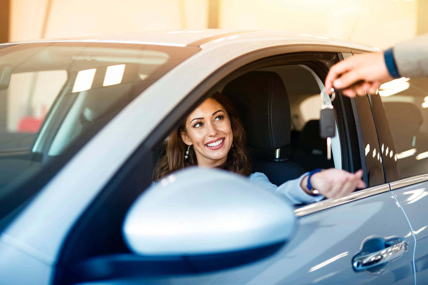 Car Images HD 桌布 壁紙 — 一位快樂的女性在經銷商展廳內從銷售人員手中接過車鑰匙，微笑著。