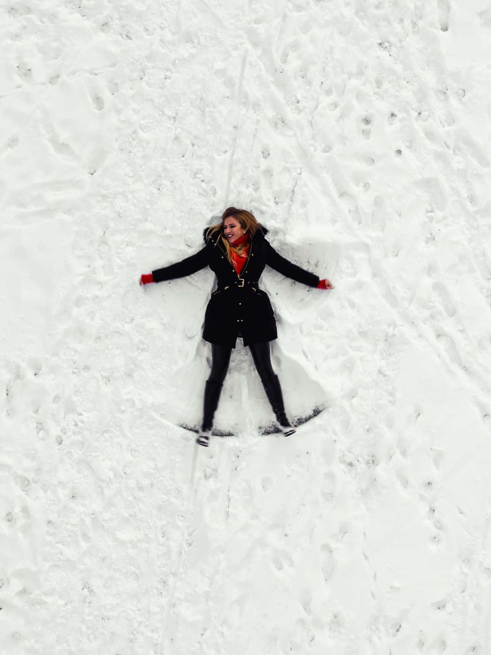 Snow Angel 桌布 壁紙 — 一位快樂的女性躺在新鮮的雪地上，張開雙臂和雙腿做出雪天使。