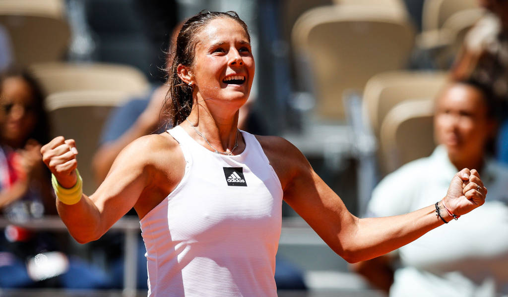 Athletic 桌布 壁紙 — 一位快樂的女網球運動員在明亮的體育場燈光下握緊拳頭慶祝勝利。