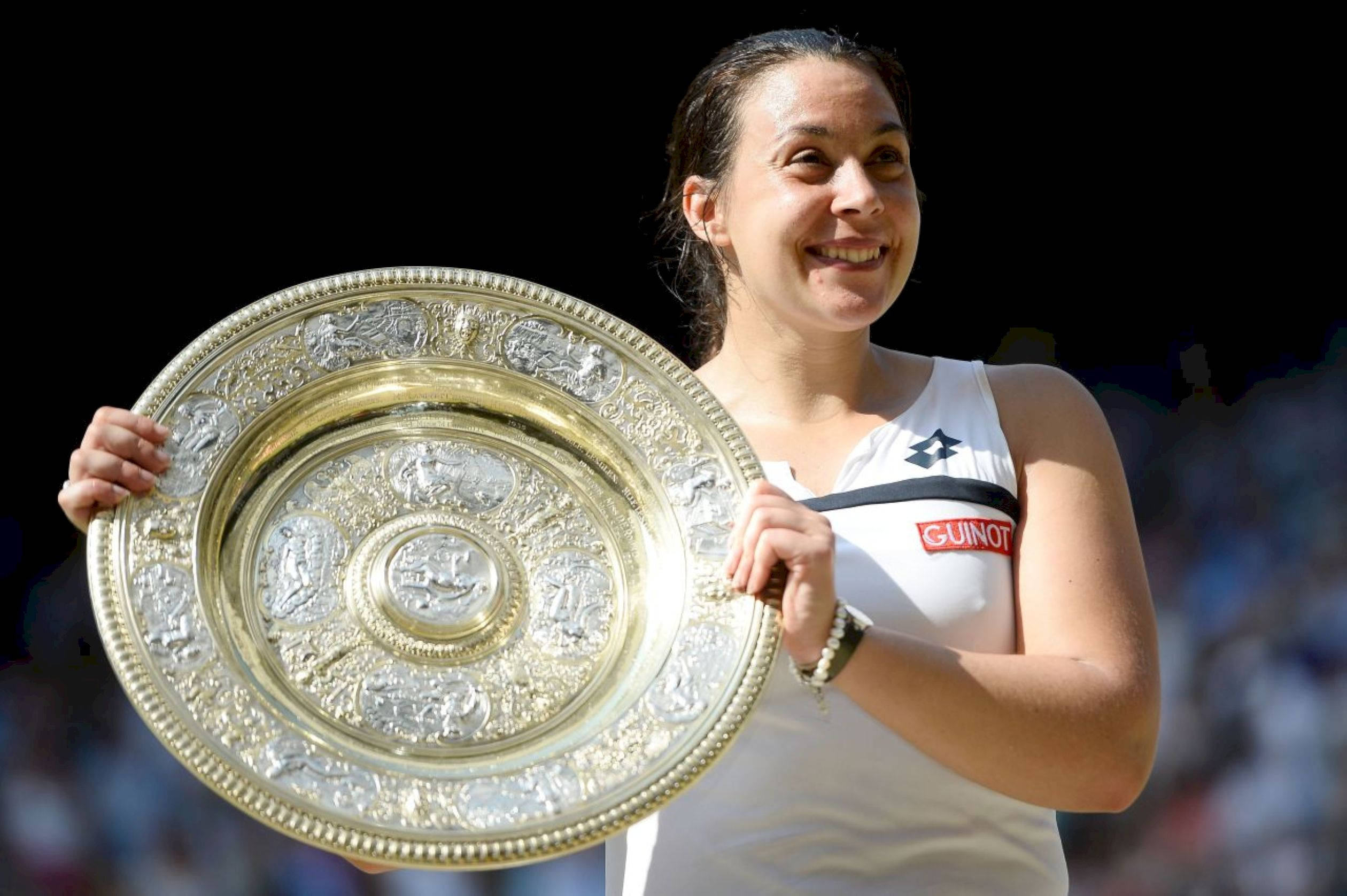 Tennis 桌布 壁紙 — 一位快樂的女網球運動員在深色背景下自豪地捧著一個華麗的大銀色獎盃，笑容燦爛。