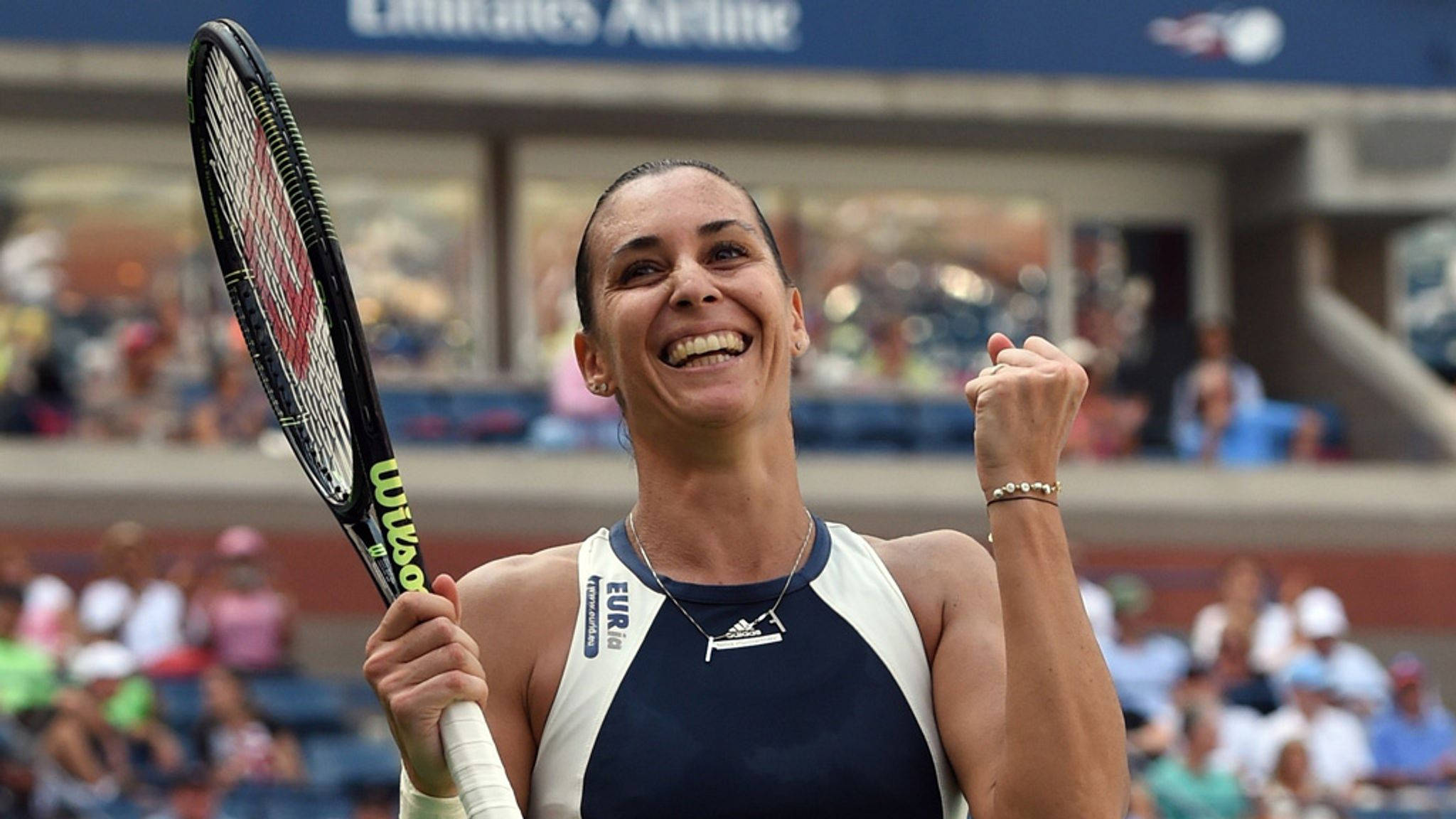Tennis 桌布 壁紙 — 一位快樂的女網球選手在陽光明媚的球場上舉起拳頭和球拍慶祝勝利。