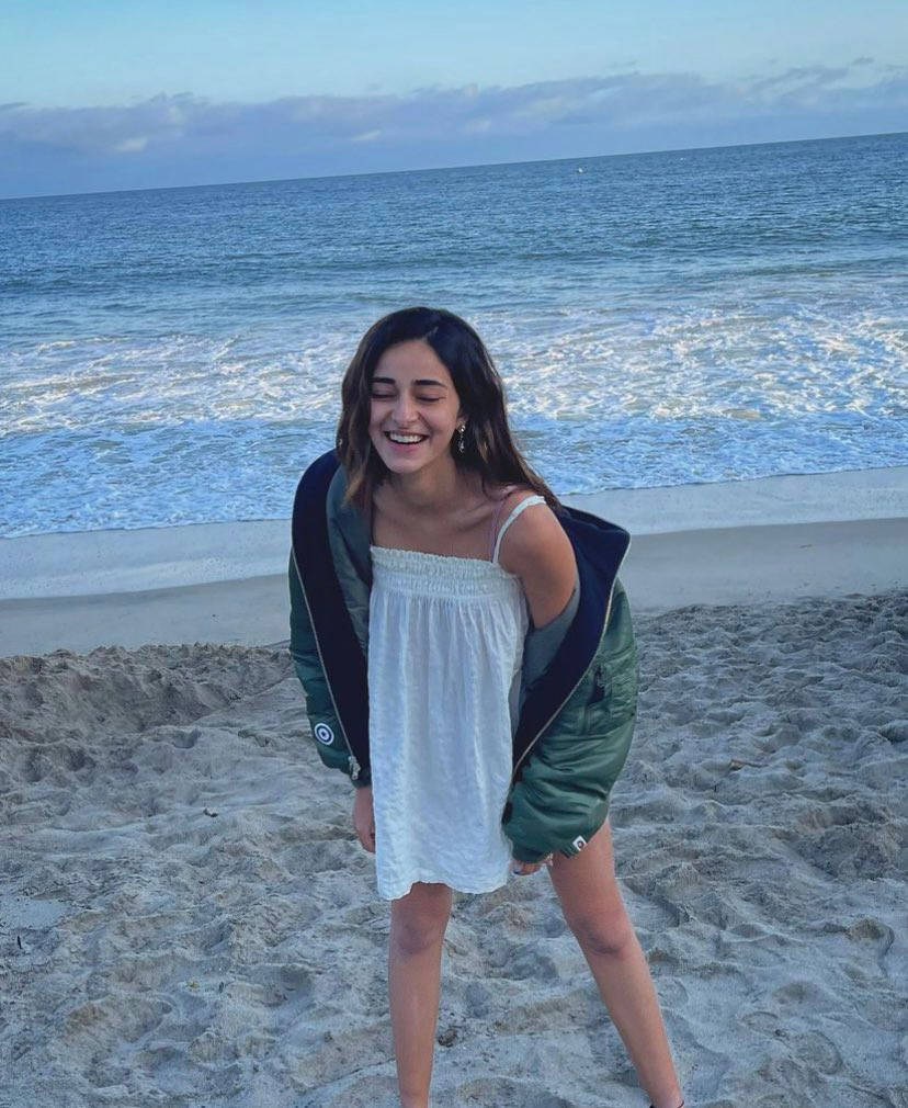 Smile 桌布 壁紙 — 一位快樂的年輕女子在沙灘上大笑，身後的海浪在柔和的暮色天空下拍打。