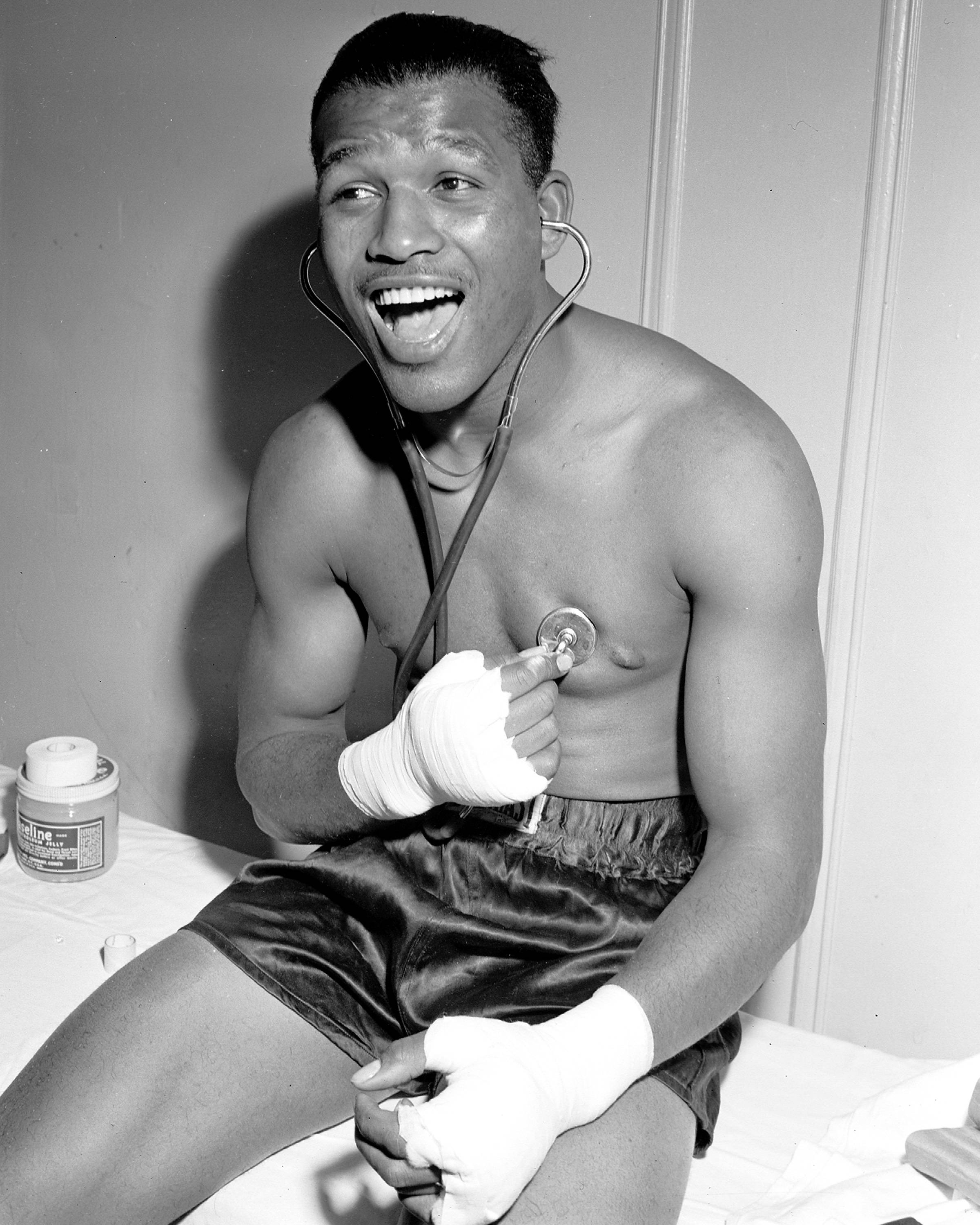 Boxing 桌布 壁紙 — 一位快樂的拳擊手穿著拳擊短褲和手帶，坐在床上頑皮地將聽診器放在胸前。