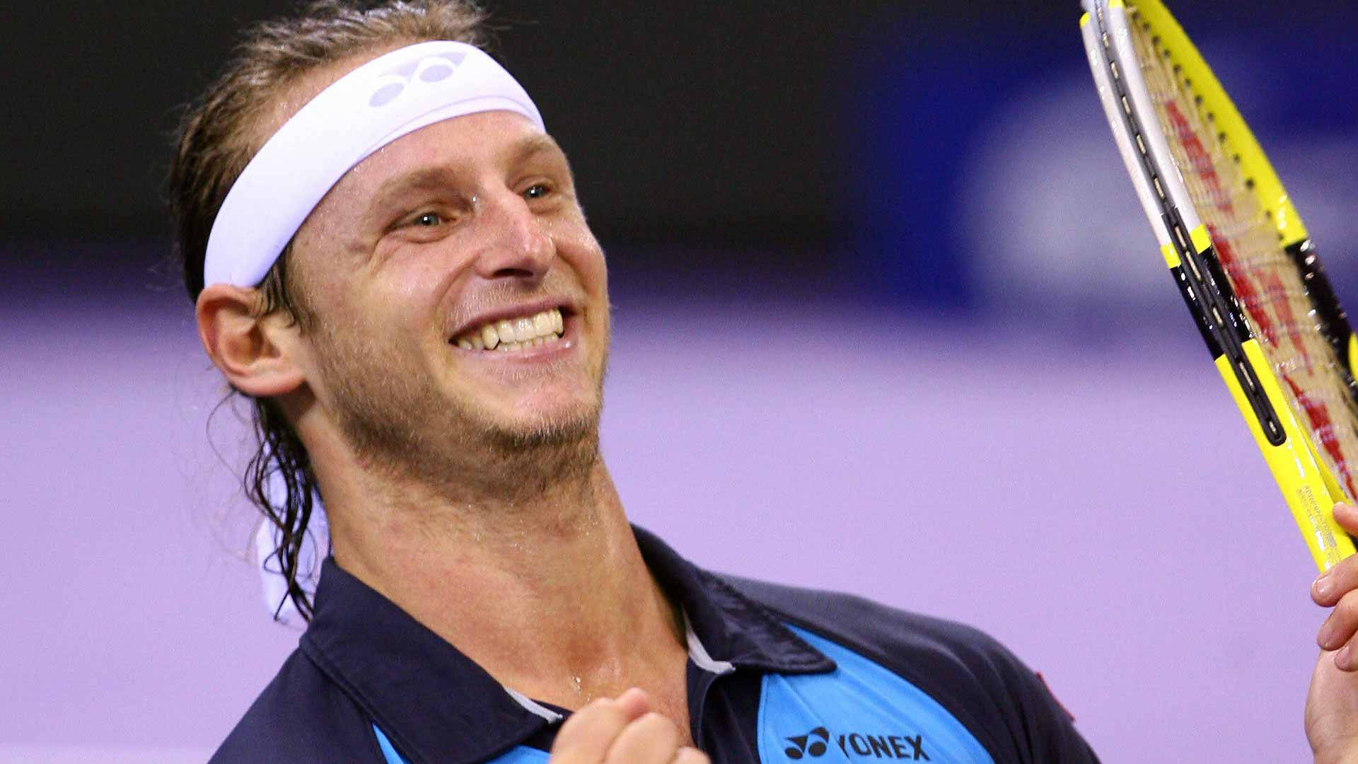 運動 桌布 壁紙 — 一位快樂的男性網球運動員在室內比賽中手持黃色球拍，露出燦爛的笑容。