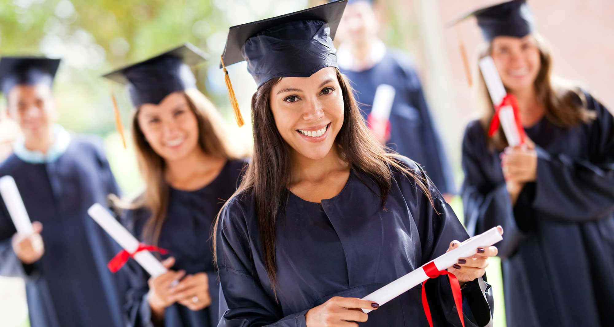 Graduation 桌布 壁紙 — 一位快樂的畢業生身穿黑色畢業袍和學士帽，手持帶有紅色絲帶的畢業證書卷，露出燦爛的笑容。