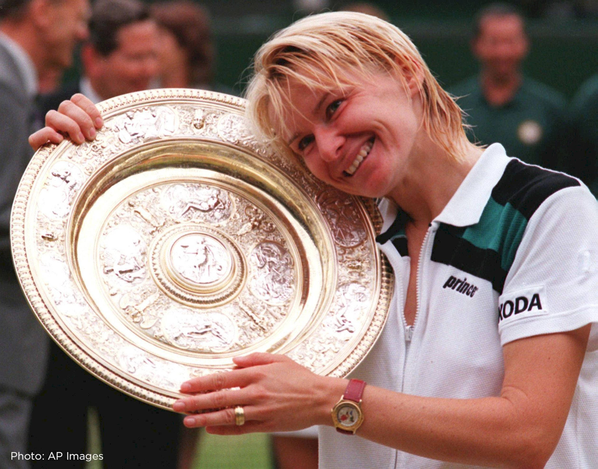 Tennis 桌布 壁紙 — 一位快樂的金髮網球選手在草地網球錦標賽中，手持一個大型華麗的銀色獎盃，笑容燦爛。