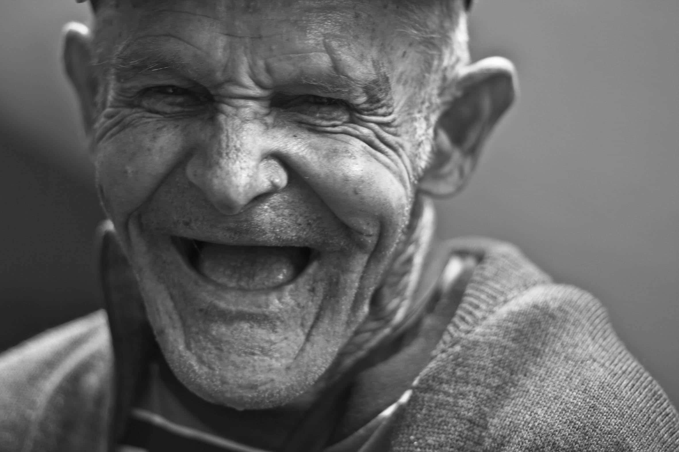 Laughing 桌布 壁紙 — 一位快樂的長者開懷大笑，深皺紋從他的眼睛放射出來，構成引人注目的黑白肖像。