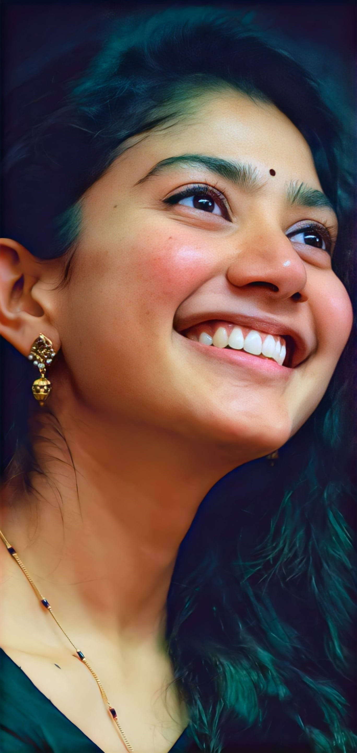 Smile 桌布 壁紙 — 一位快樂的黑髮女子戴著金色耳環，在深藍綠色背景前燦爛微笑。