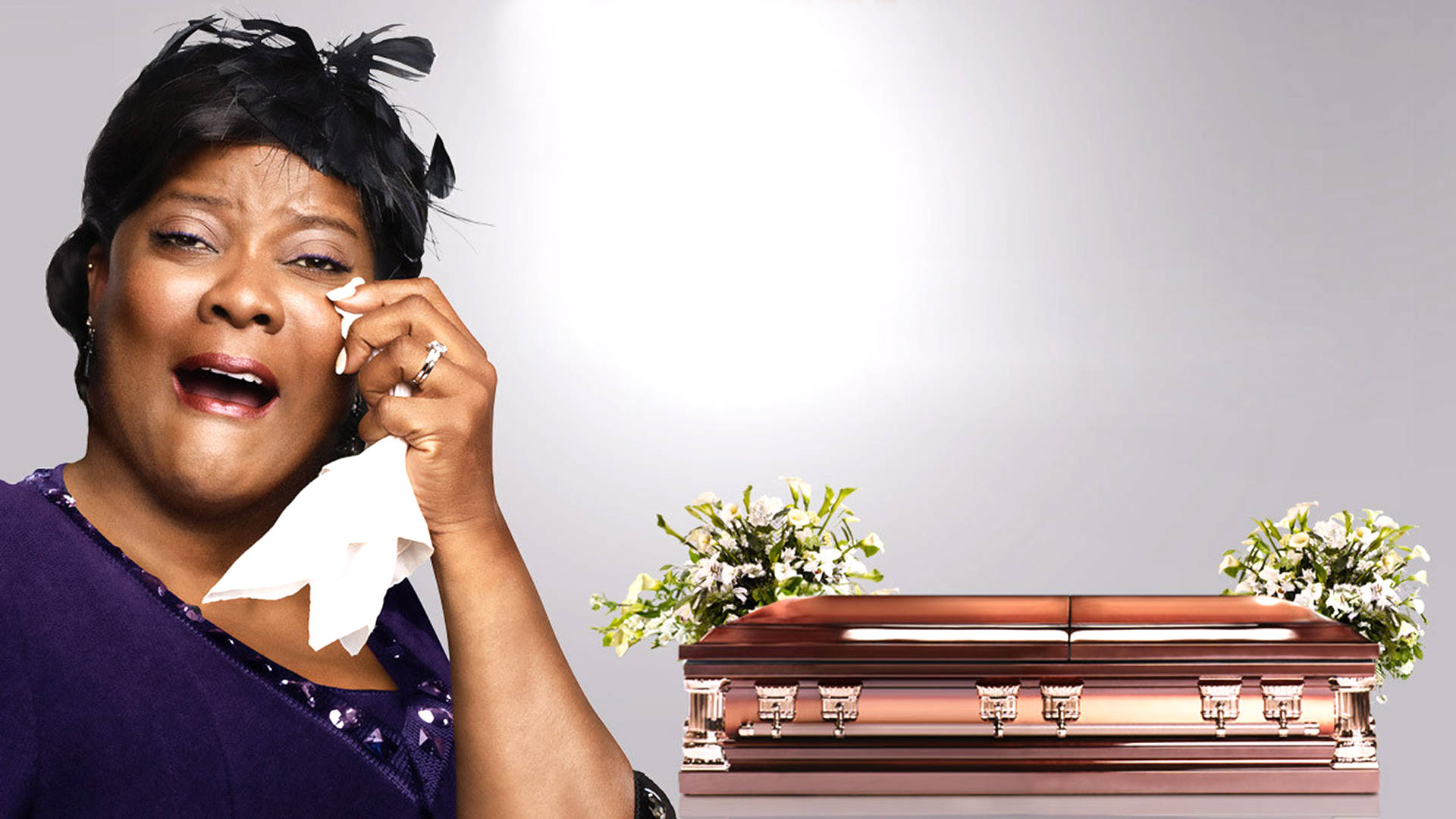 Funeral 桌布 壁紙 — 一位悲傷的女性用紙巾擦拭眼淚，旁邊是拋光青銅棺木，飾有白色花卉佈置。