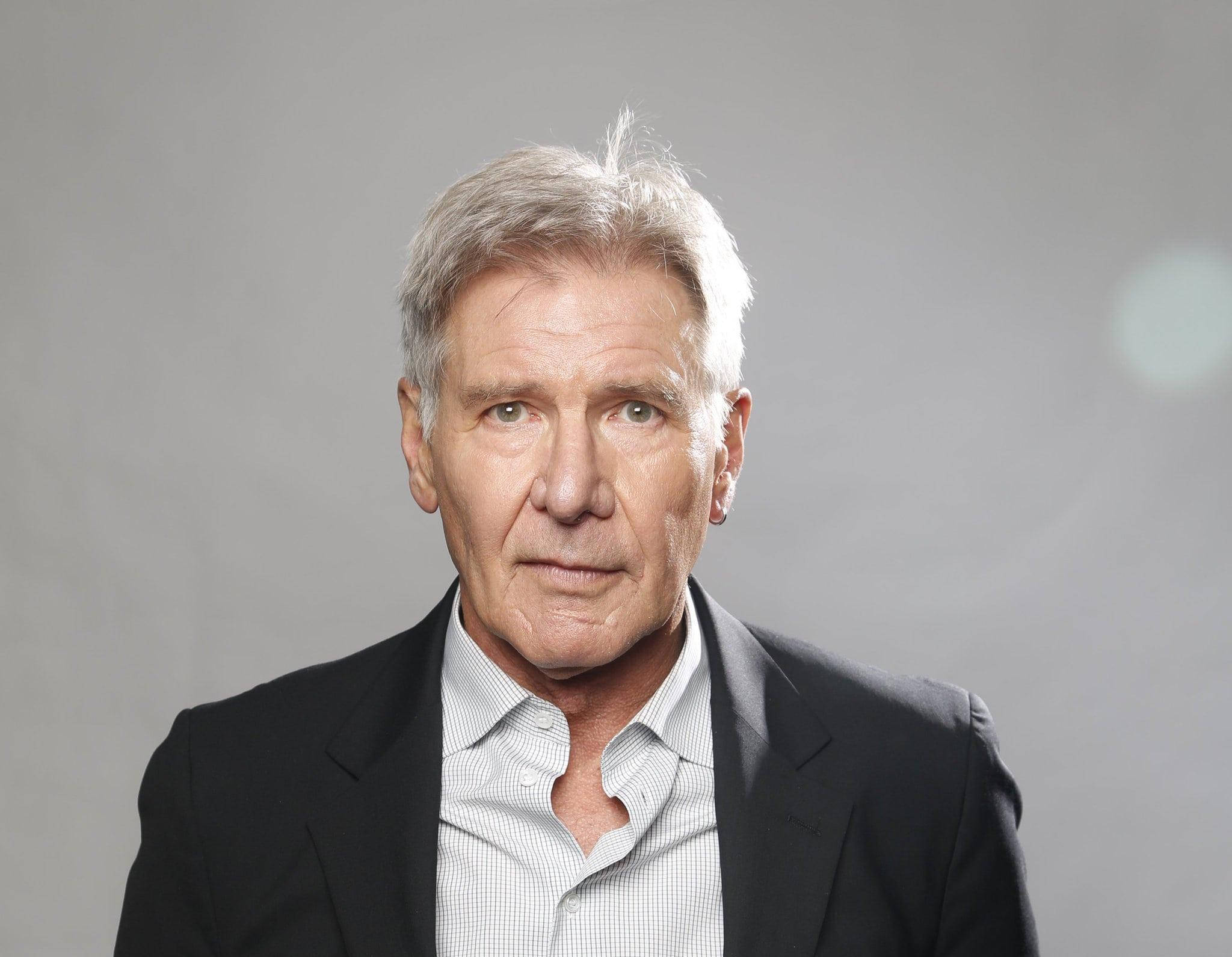 han solo 桌布 壁紙 — 一位成熟男士的頭像特寫，灰白頭髮，身穿深色西裝和淺色襯衫，背景為中性灰色。