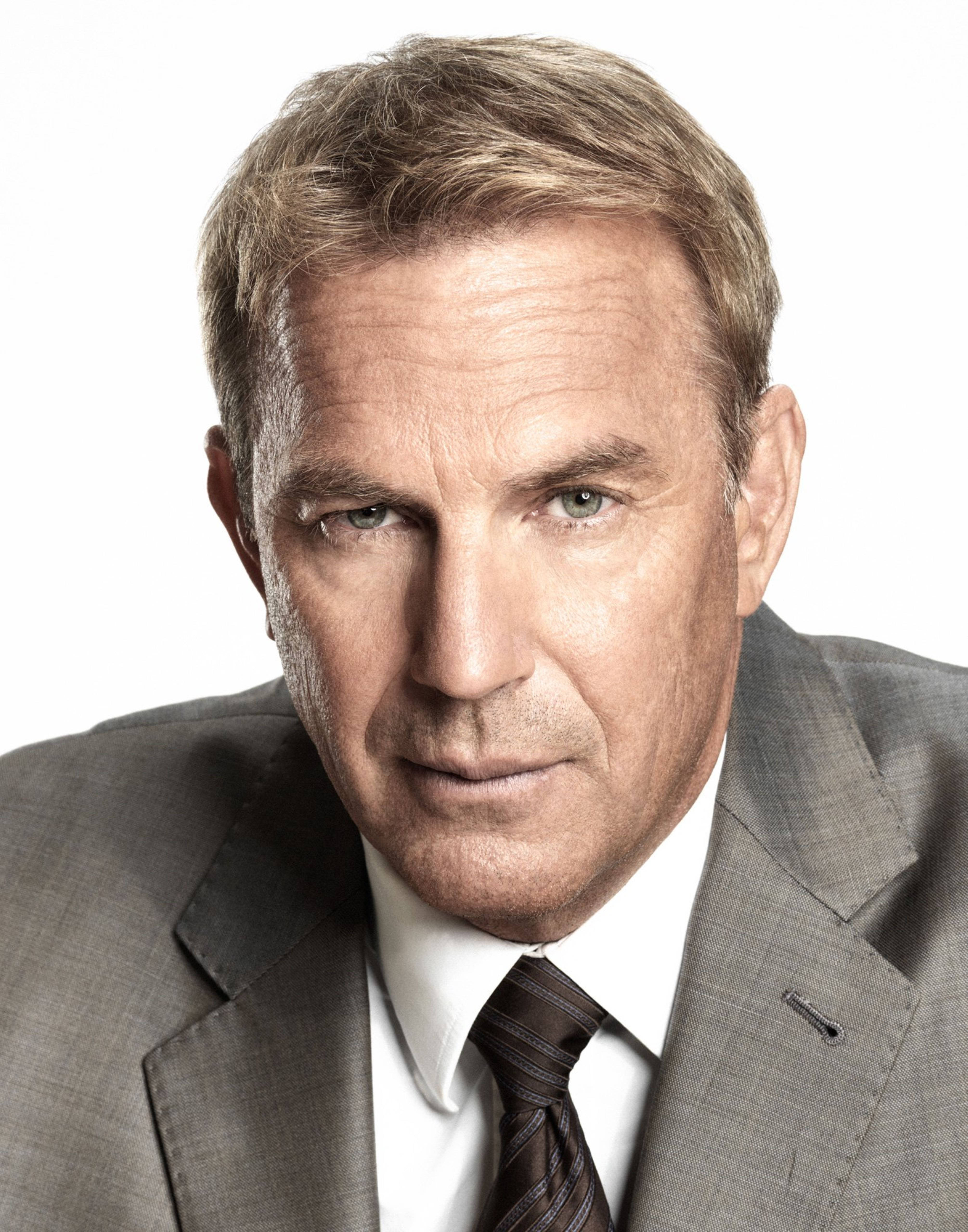 Kevin Costner 桌布 壁紙 — 一位成熟男士的頭像特寫，身穿灰色西裝和條紋領帶，背景為純白色。
