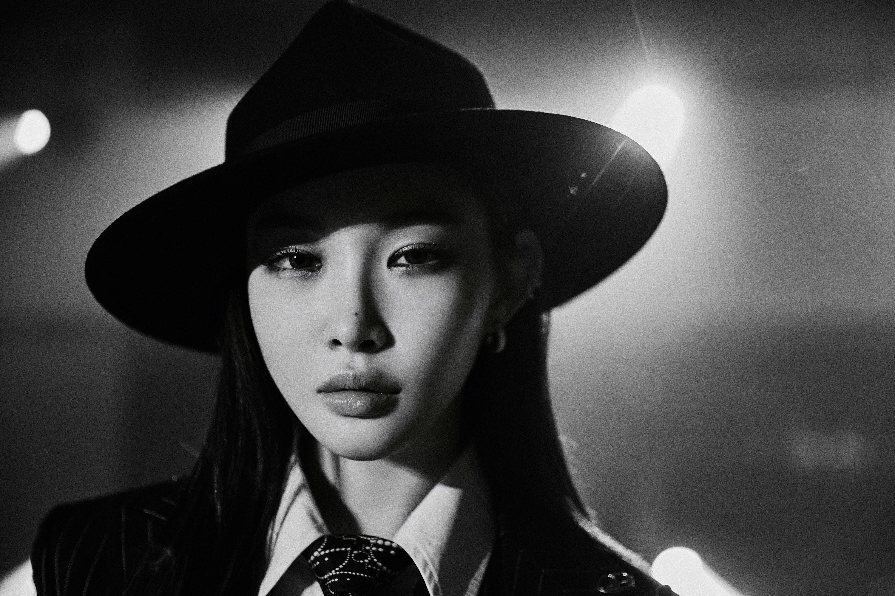 Chungha 桌布 壁紙 — 一位戴寬邊帽的女性的引人注目的黑白肖像，具有戲劇性的燈光和強烈的凝視。