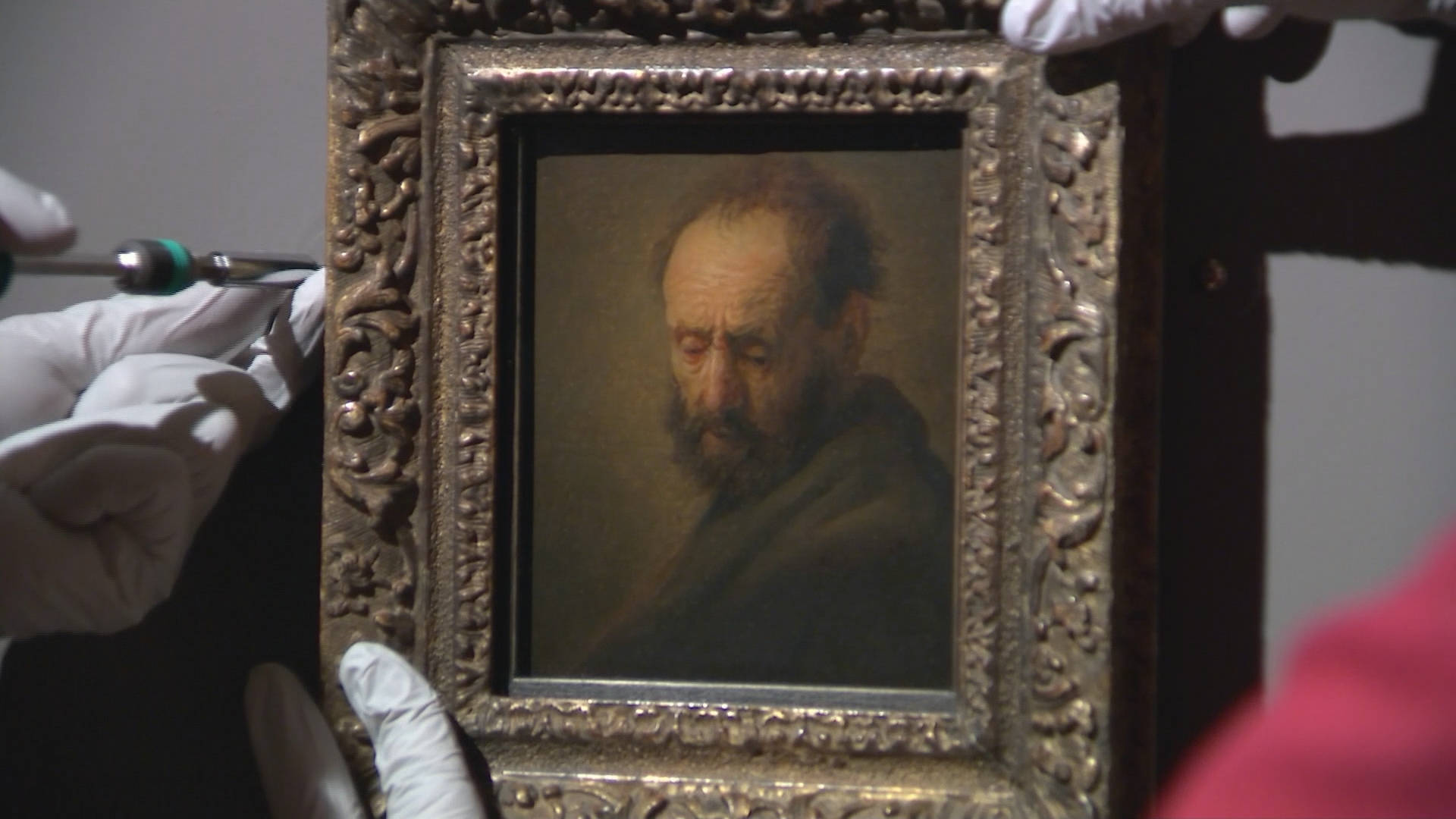 Rembrandt 桌布 壁紙 — 一位戴白手套的修復師使用工具小心地修復一幅鑲在鍍金畫框中的鬍鬚男子舊油畫。