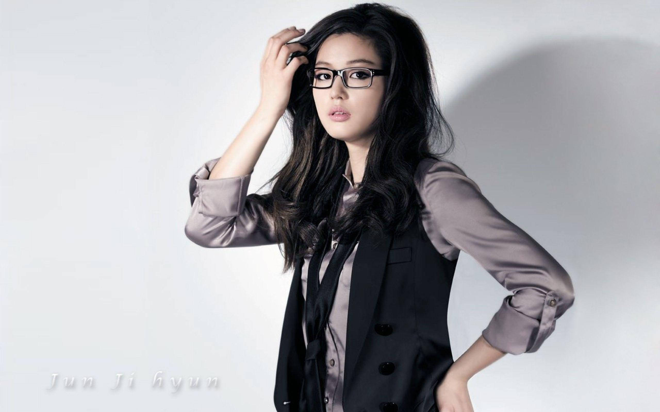 Jun Ji Hyun 桌布 壁紙 — 一位戴眼鏡、深色頭髮的優雅女性，在純白攝影棚背景前自信地擺姿勢。