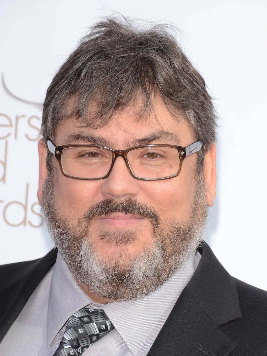 Paul Dini 桌布 壁紙 — 一位戴眼鏡、留灰白鬍鬚的男士在頒獎典禮上穿著西裝和圖案領帶的特寫肖像。
