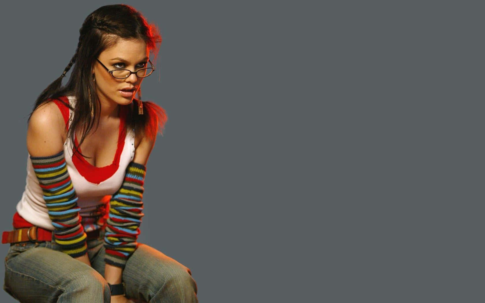 Rachel Bilson 桌布 壁紙 — 一位戴眼鏡、穿著彩色條紋臂套的年輕女子在純灰色背景前自信地擺姿勢。