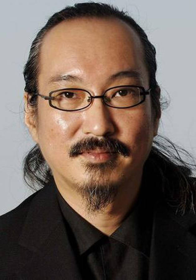 satoshi kon 桌布 壁紙 — 一位戴眼鏡和鬍子的男士，身穿黑色西裝，背景為純灰色。